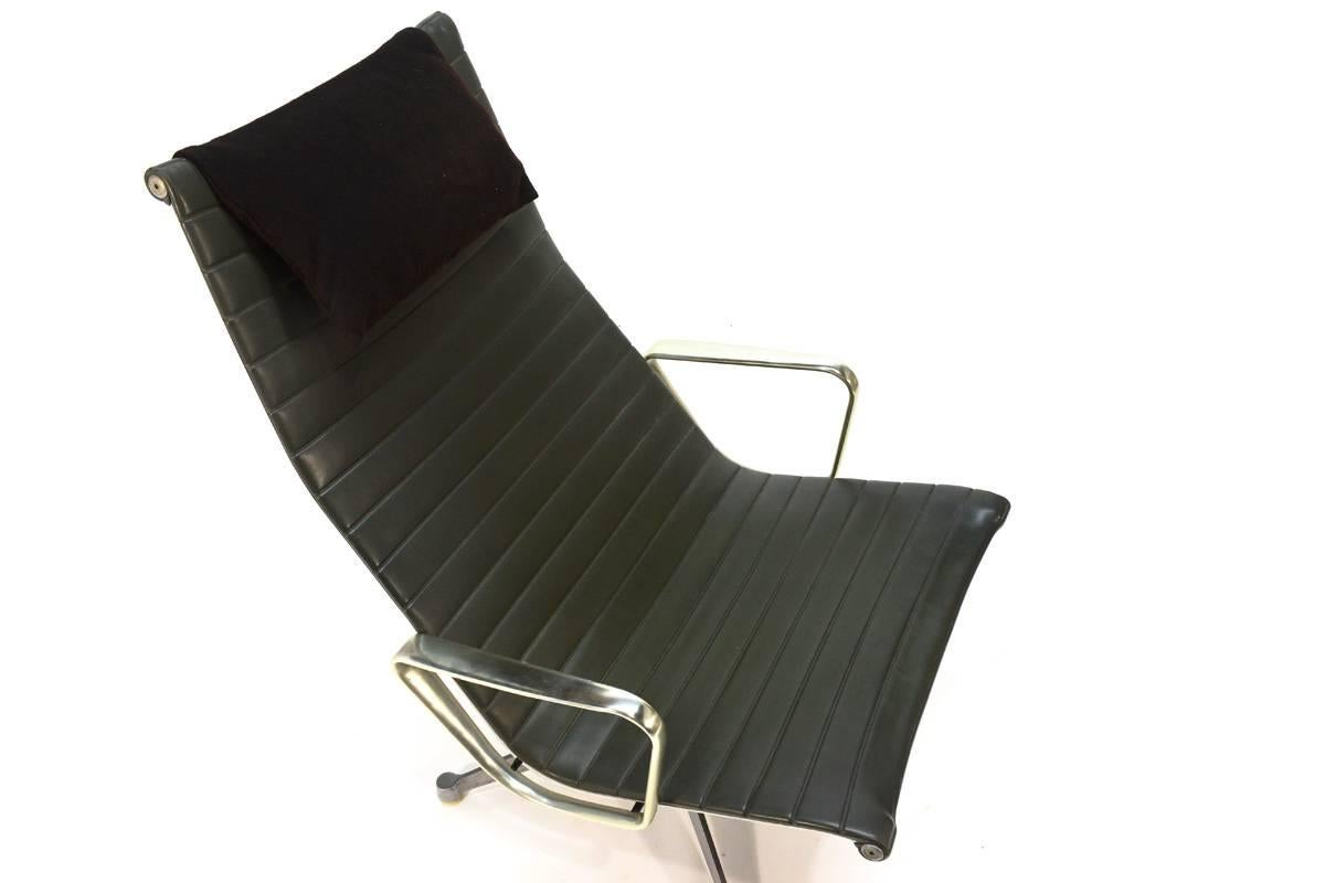 Aluminium group lounge chair and designed by Charles and Ray Eames for Herman Miller. This example has the earlier tilt and swivel base. The vinyl seat is all original with no significant stretching, it appears to be a very dark green, not quite