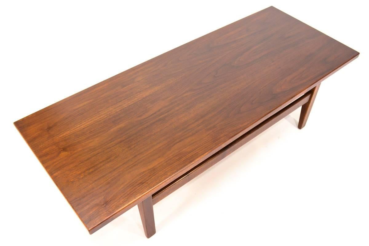 Walnut coffee table designed by Jens Risom. Beautiful piece, utilizing some fantastic walnut as most of his pieces did. A very clean and simple design that gives the illusion of a floating top. This piece is in excellent original