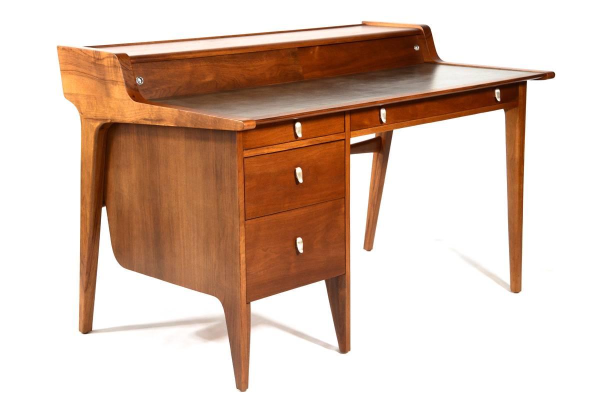 Beautiful desk in walnut and leather designed by John Van Koert as part of the Drexel Profile line of furniture that was produced from 1955-1961. This was the largest desk from that line. This desk makes a statement from any angle with its sweeping