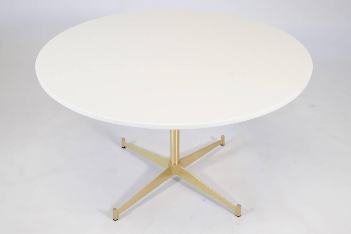 A rare table designed by Paul McCobb for Directional, circa 1950s. Features a 42" round Vitrolite glass top and brass plated aluminum base. This piece sits slightly lower than a standard dining table, but the center shaft of the base could be