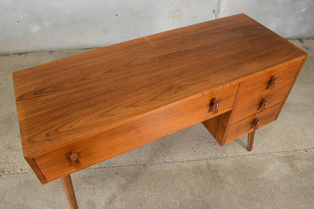 Very nice little desk designed by Stanley Young for Glenn of California. It is a very clean Classic early modernist design. Features sculpted walnut pulls that are floating off the face with brass spacers. This desk also has a finished walnut back