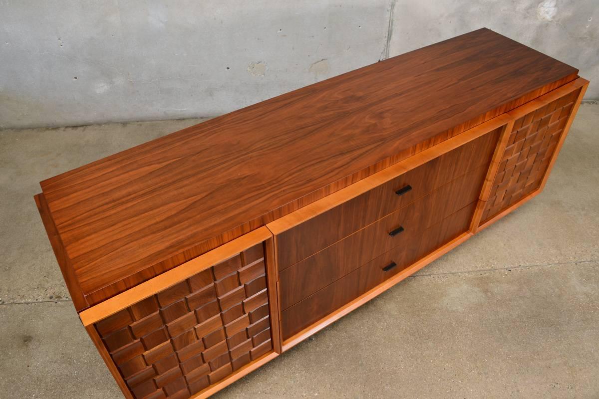A fantastic large walnut dresser with a Brutalist or checkerboard walnut block detail on the side doors. The walnut blocks are all sculpted with raised edges, it gives the doors a very three dimensional look. Behind each of the doors is three