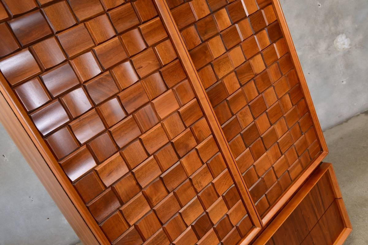 A fantastic large walnut armoire with a Brutalist or checkerboard walnut block detail on the upper doors. The walnut blocks are all sculpted with raised edges, it gives the doors a very three dimensional look. The color and grain of the walnut