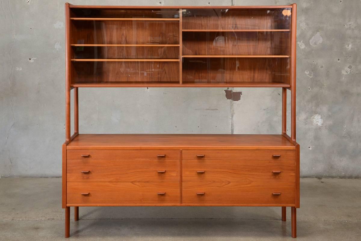 Large teak sideboard designed by Hans Wegner for Ry Mobler in 1953. This piece features the less common glass upper doors. It is in original condition with very light normal wear. Can be disassembled for easier transport.

Measures: 71
