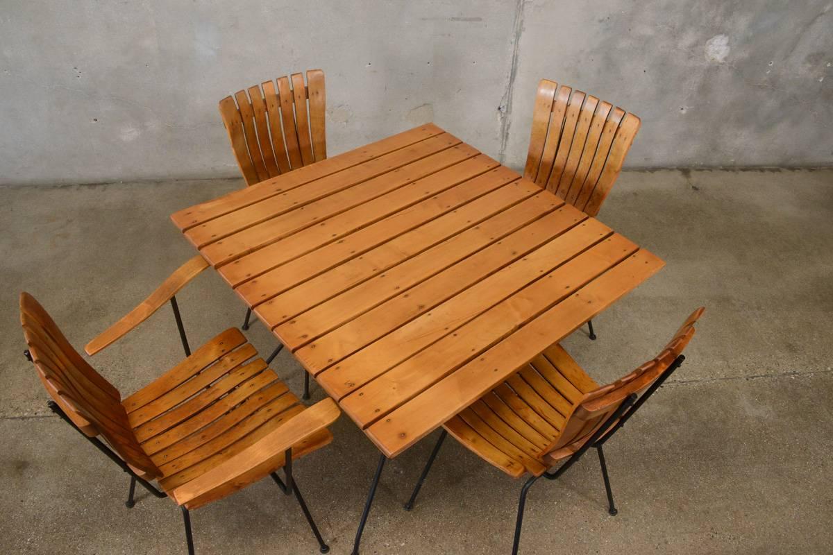 A dining set by Arthur Umanoff in slatted maple and iron. Includes a square table, three side chairs and one armchair. The chairs are a less common model with slatted seats and backs. Would be great set for a breakfast area, small dining area, or