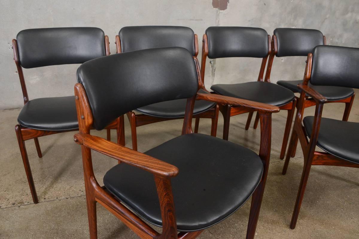 Beautiful set of six Erik Buck model 49 rosewood dining chairs produced by O.D. Mobler. The set includes four side chairs and a pair of the desirable arm chairs. These have been recovered with new black vinyl upholstery. The frames are in nice
