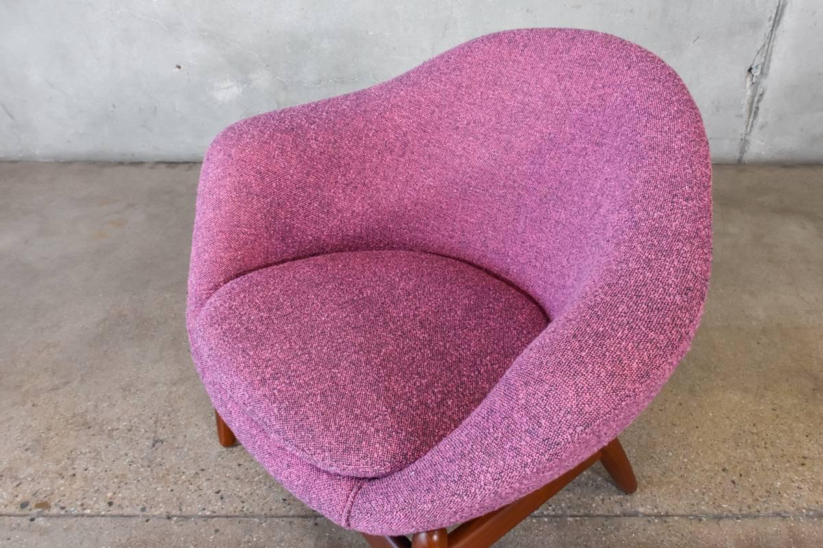 An uncommon lounge chair designed by Kofod-Larsen. A pod shaped seat created in foam sits over sculpted teak legs. A very unique look. This piece has been reupholstered in a fantastic vintage nubby fabric, it falls somewhere between pink and purple.