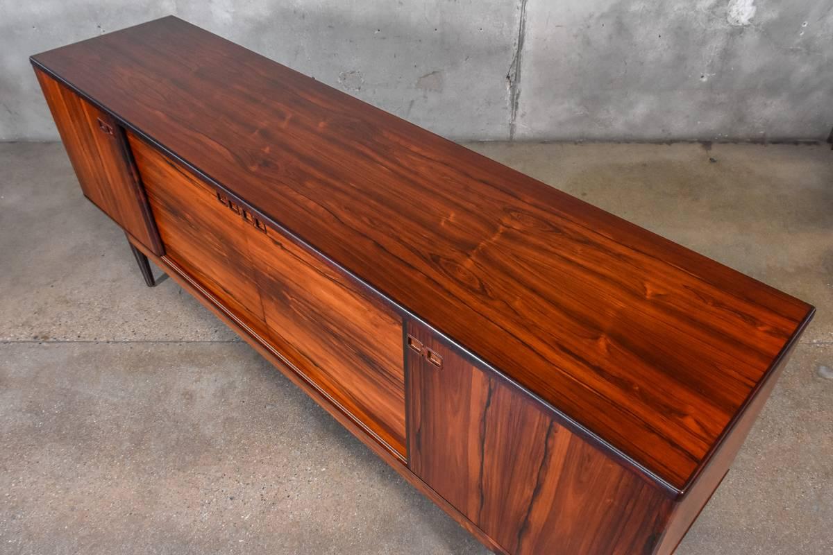 A stunning large scale credenza in rosewood by Christian Linneberg. Absolutely fantastic color and grain across the entire piece. Behind the four sliding doors are a multitude of adjustable shelves and drawers. This piece has been completely