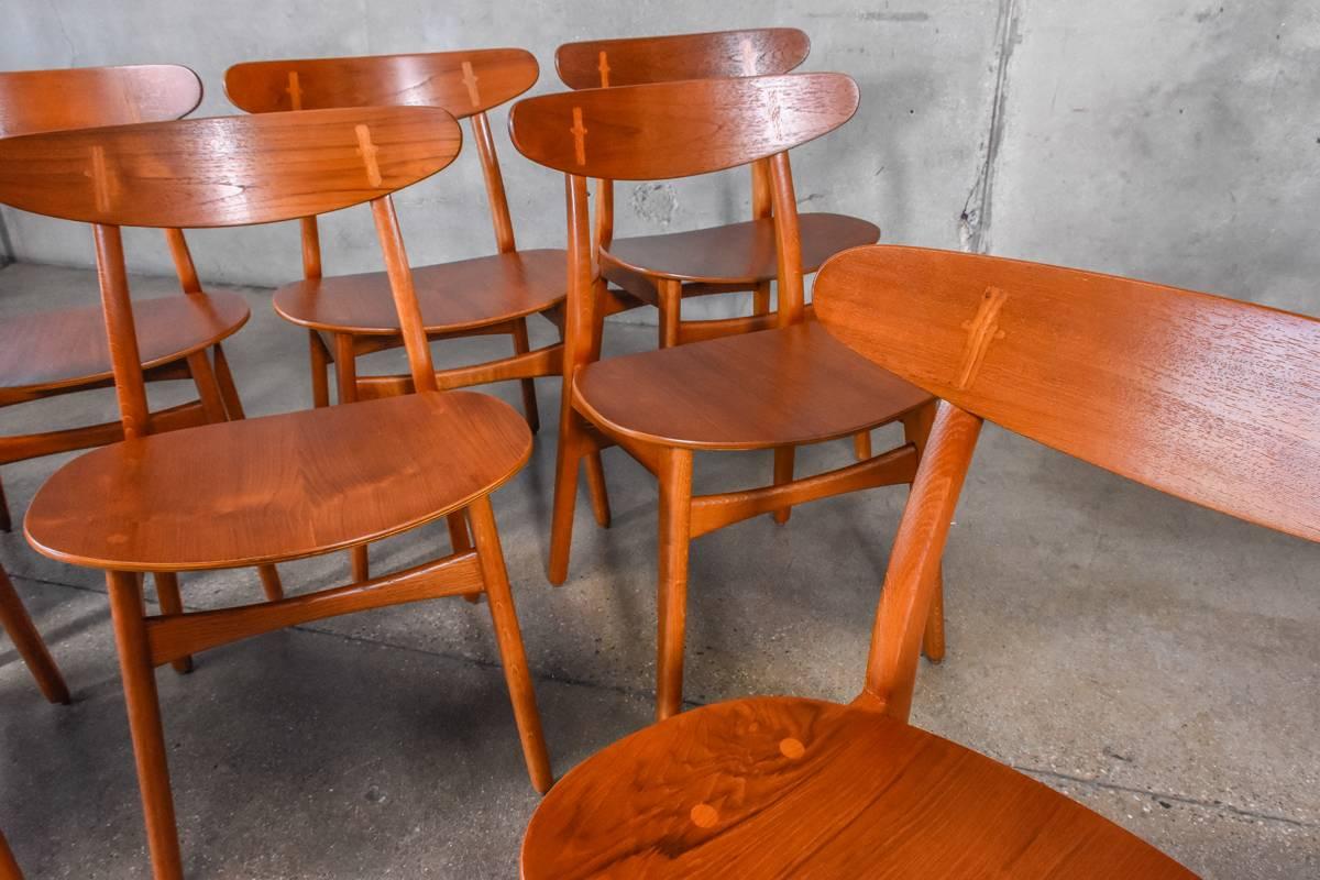 A set of eight CH-30 dining chairs designed by Hans Wegner in 1952 and produced by Carl Hansen & Son in Denmark. The finished teak seat and backrest paired with the solid oak frame make these the more uncommon variation of this chair. These have