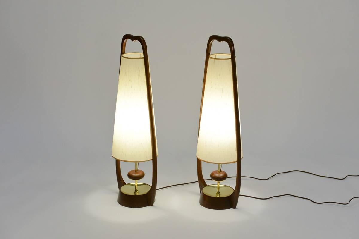 Beautiful pair of sculptural wood table lamps by Modeline. All original and in excellent condition. These lamps have the unique feature of being controlled (on/off) by floating wood disc that wraps around the center brass upright. The original