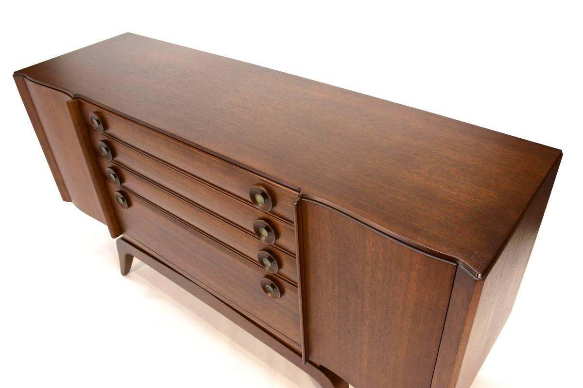 Gorgeous early 1940s buffet by modern Pioneer, Gilbert Rohde (1894–1944), for Brown Saltman. Constructed of solid mahogany with fantastic details in the pulls and along the front edge. The piece has plenty of storage between three drawers. The drop