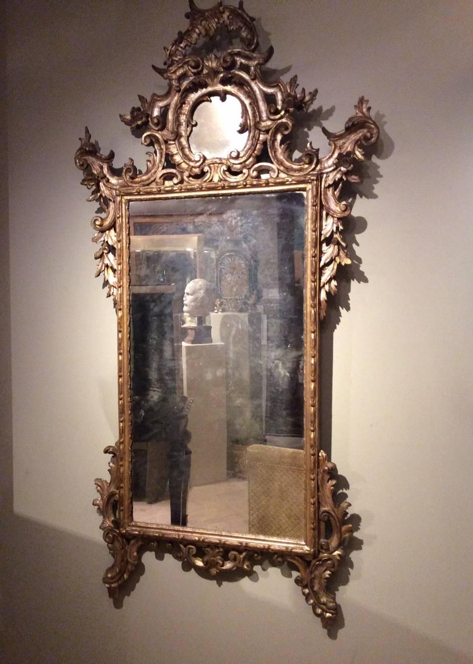 18th century venetian mecca giltwood mirror. 
Mirror with pediment , gilded and carved wood frame decorated with lush curls of foliage, shells and scrolls.
Mercury mirror.
Venice second half of the 18th century.
Reinforcements in the upper rear
