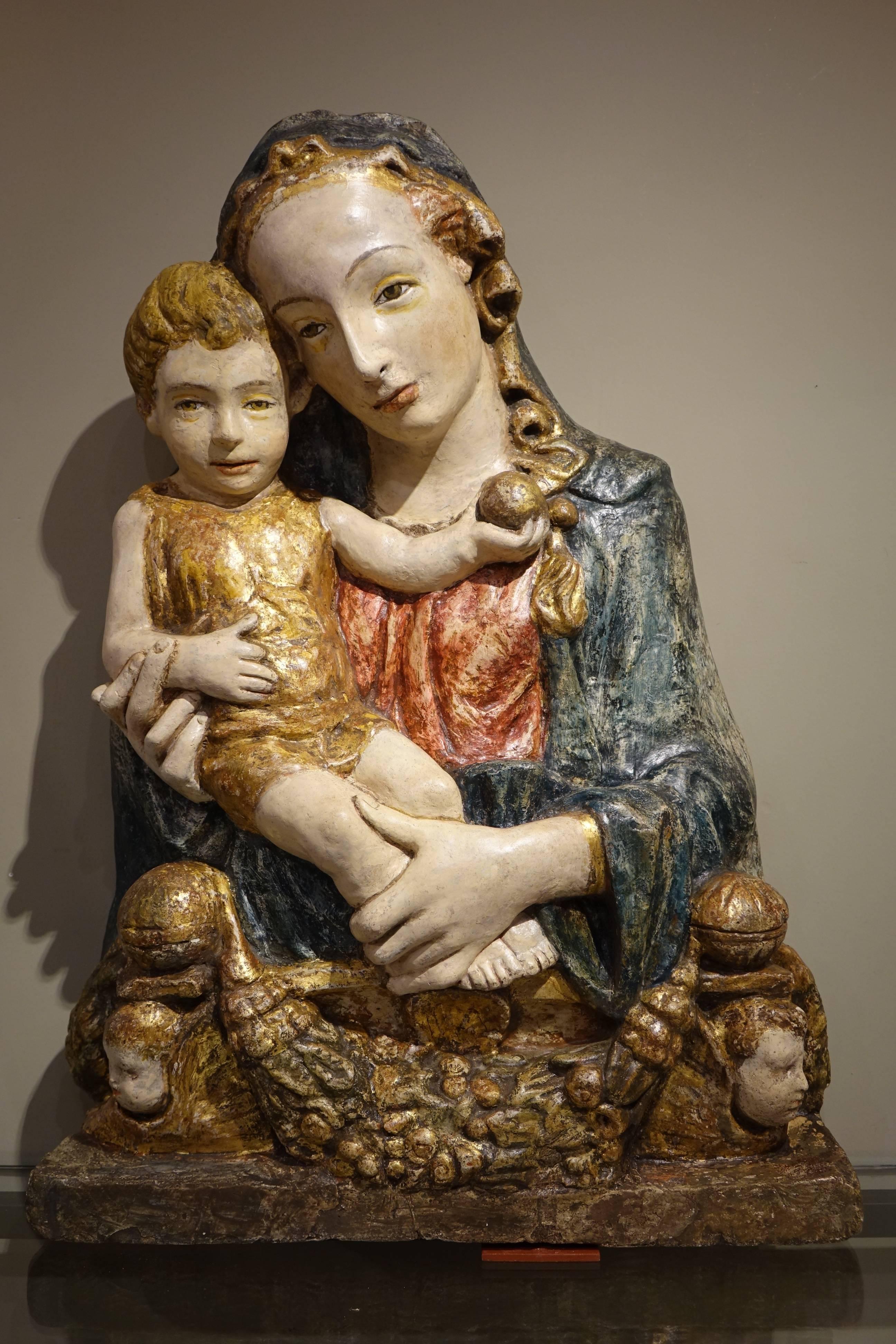 Large and beautiful, rare sculpture of  Virgin and Child, in relief, executed in painted and gilt stucco, resting on a base framed by two winged angels surrounding a garland of flowers.
The stucco technique, made of  gypsum, dates back to antiquity,