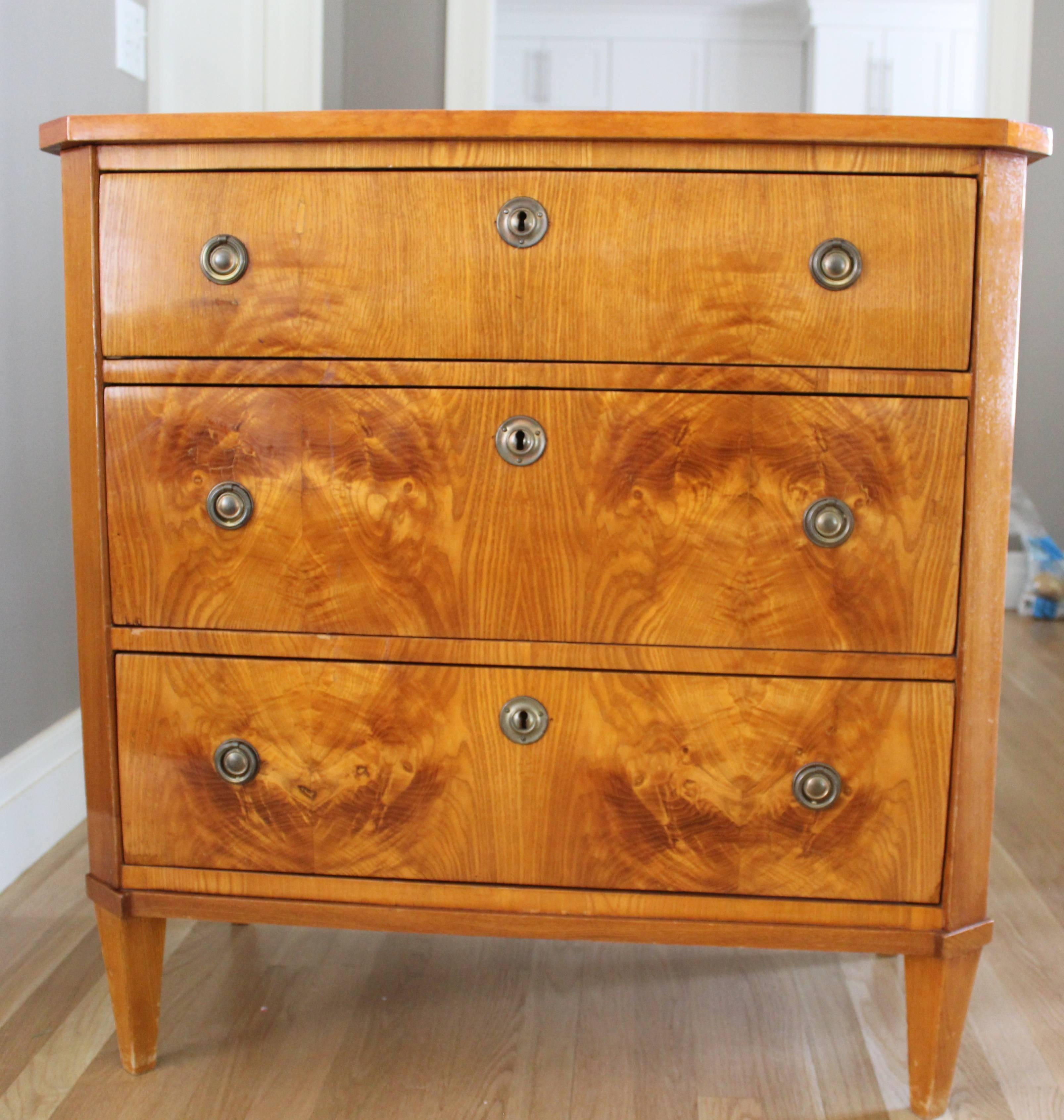 Classic Gustavian chest of drawers, elmwood veneer with beautiful mirrored design on the front, three central drawers, original pulls and escutcheons ending on tapered square legs. In good condition.