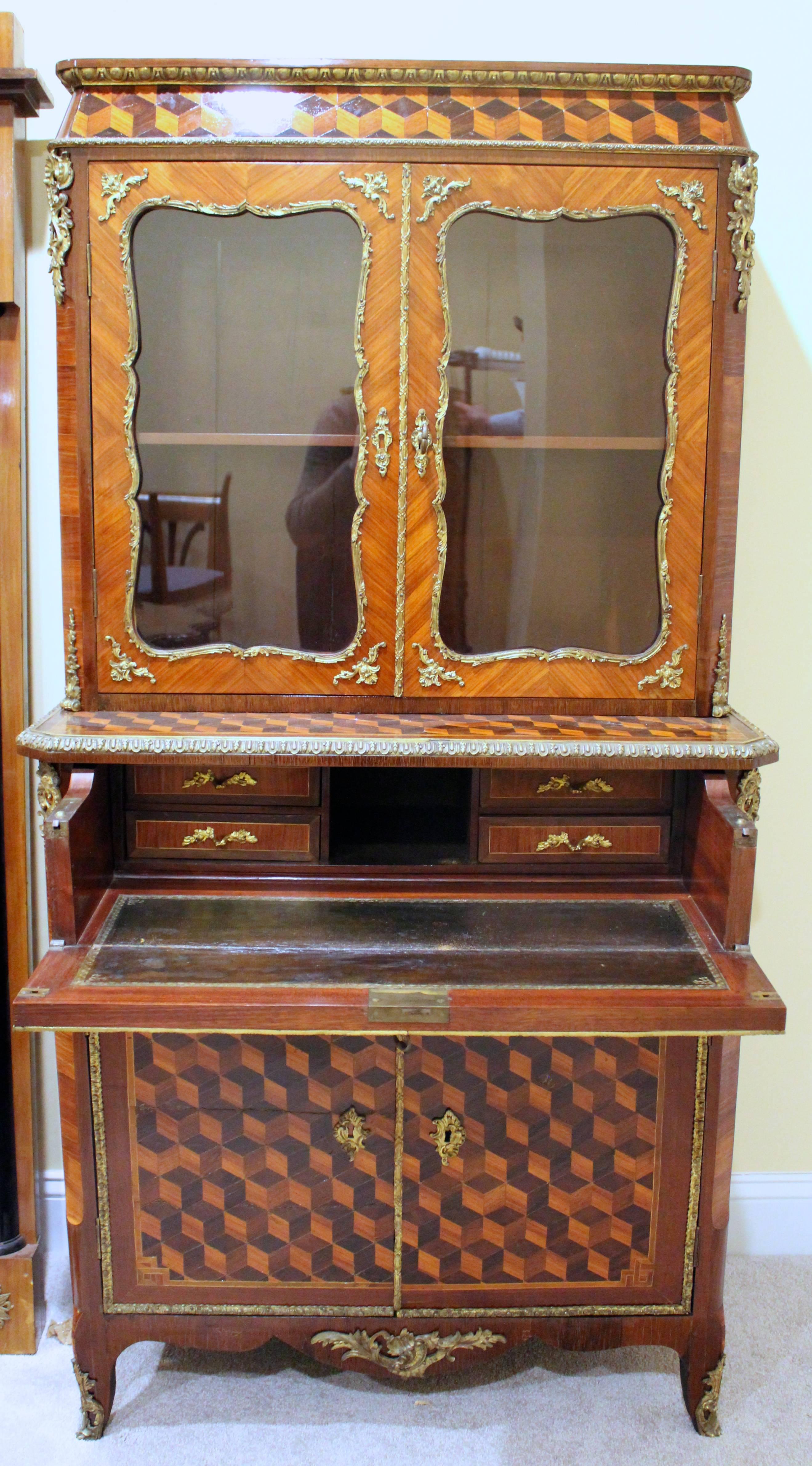 Voici une armoire vraiment exceptionnelle avec un bureau caché. Ce meuble exquis présente une combinaison captivante de marqueterie de bois de rose, de bois de roi et de blocs d'acajou, créant une présentation visuellement éblouissante. Des montures