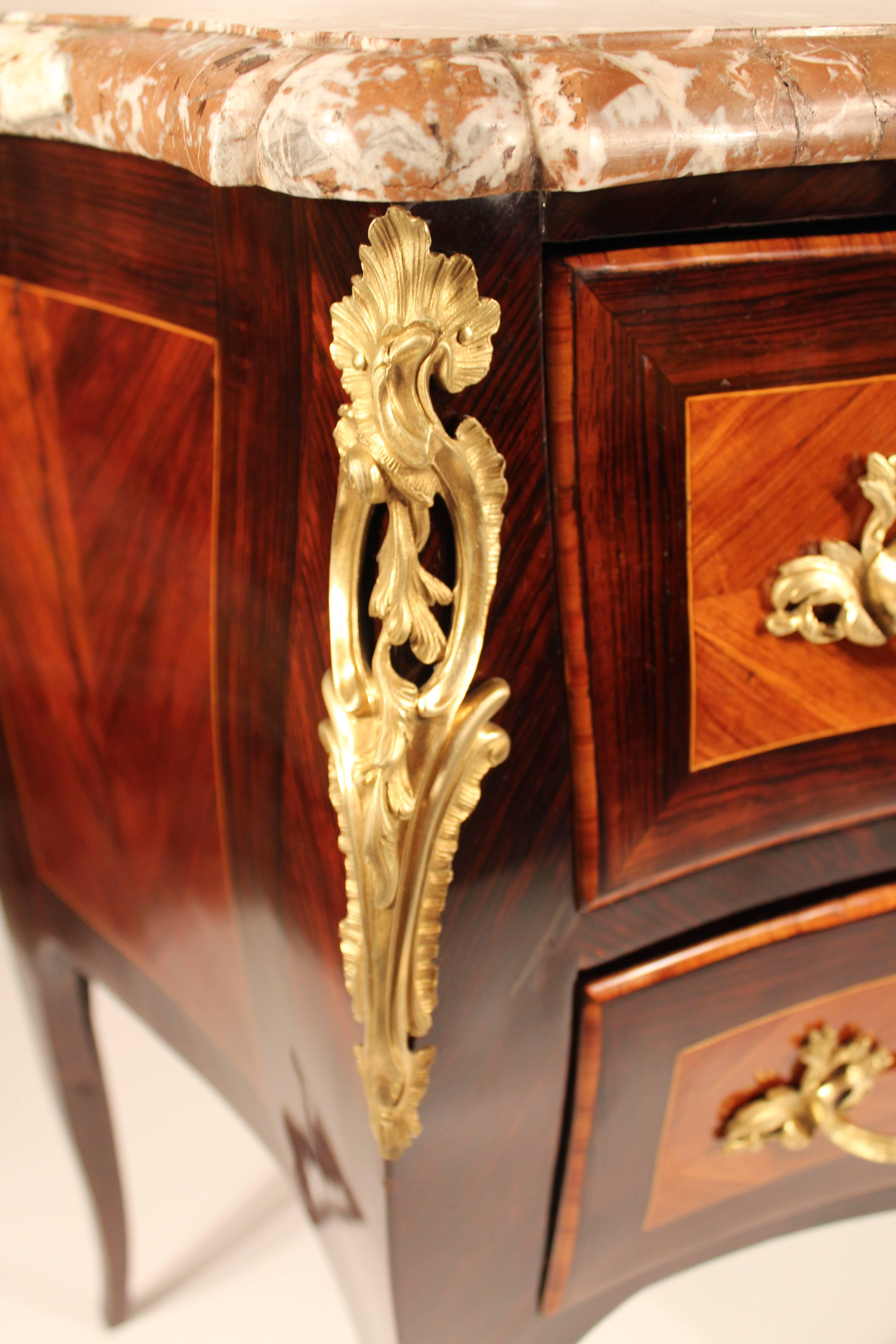 Fine Louis XV commode raised on tapering legs with scrolled caps. Bombé front with three drawers, one large and two smaller ones on the upper part. Brilliantly grained rosewood and kingwood veneer with gold-plated bronze fittings, beautifully formed