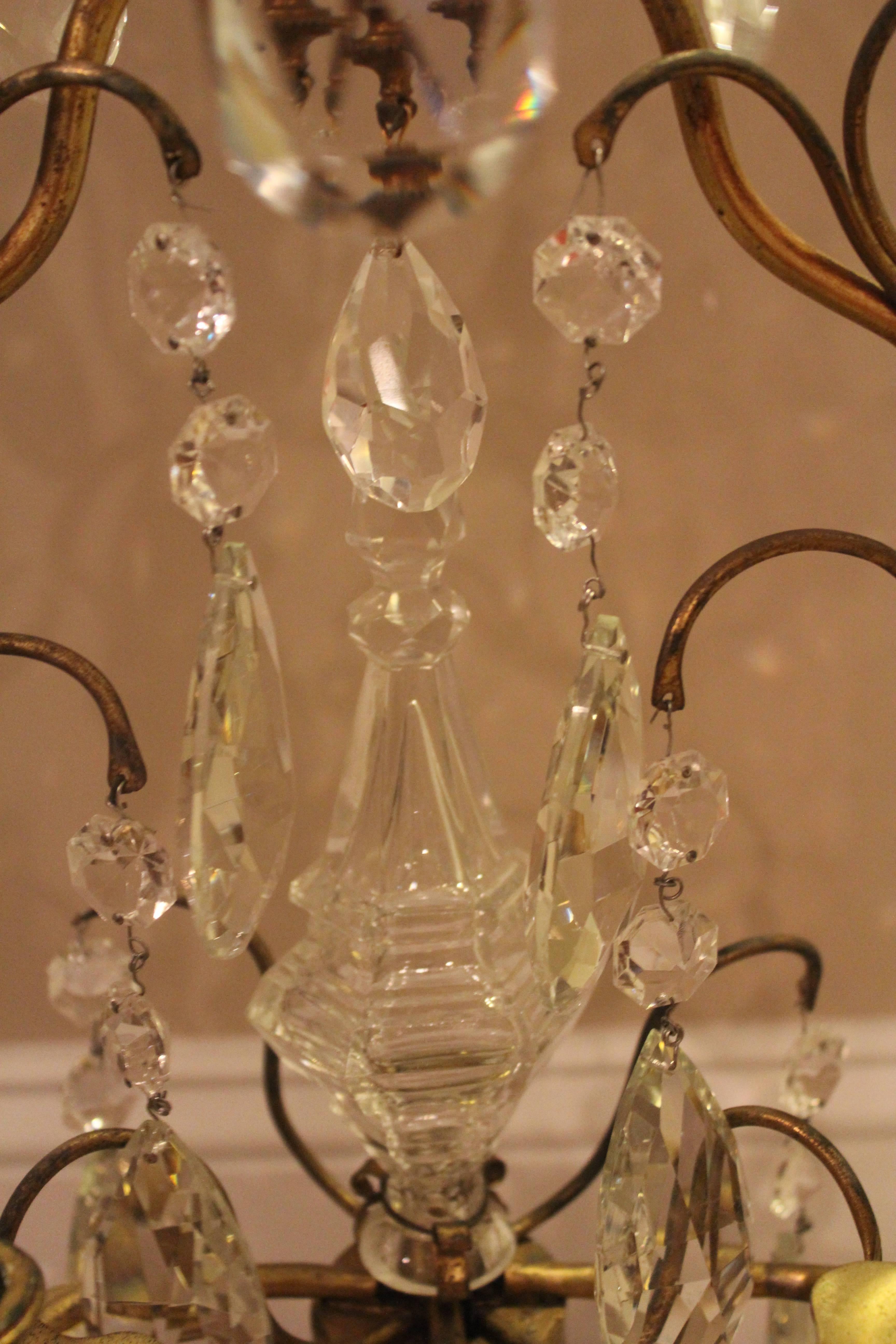 Kontinentaler fünfflammiger Kandelaber aus Bronze und geschliffenem Glas mit geschwungenen Armen, mehrteiligen Glastropfen und blumenförmigen Kerzenschalen.