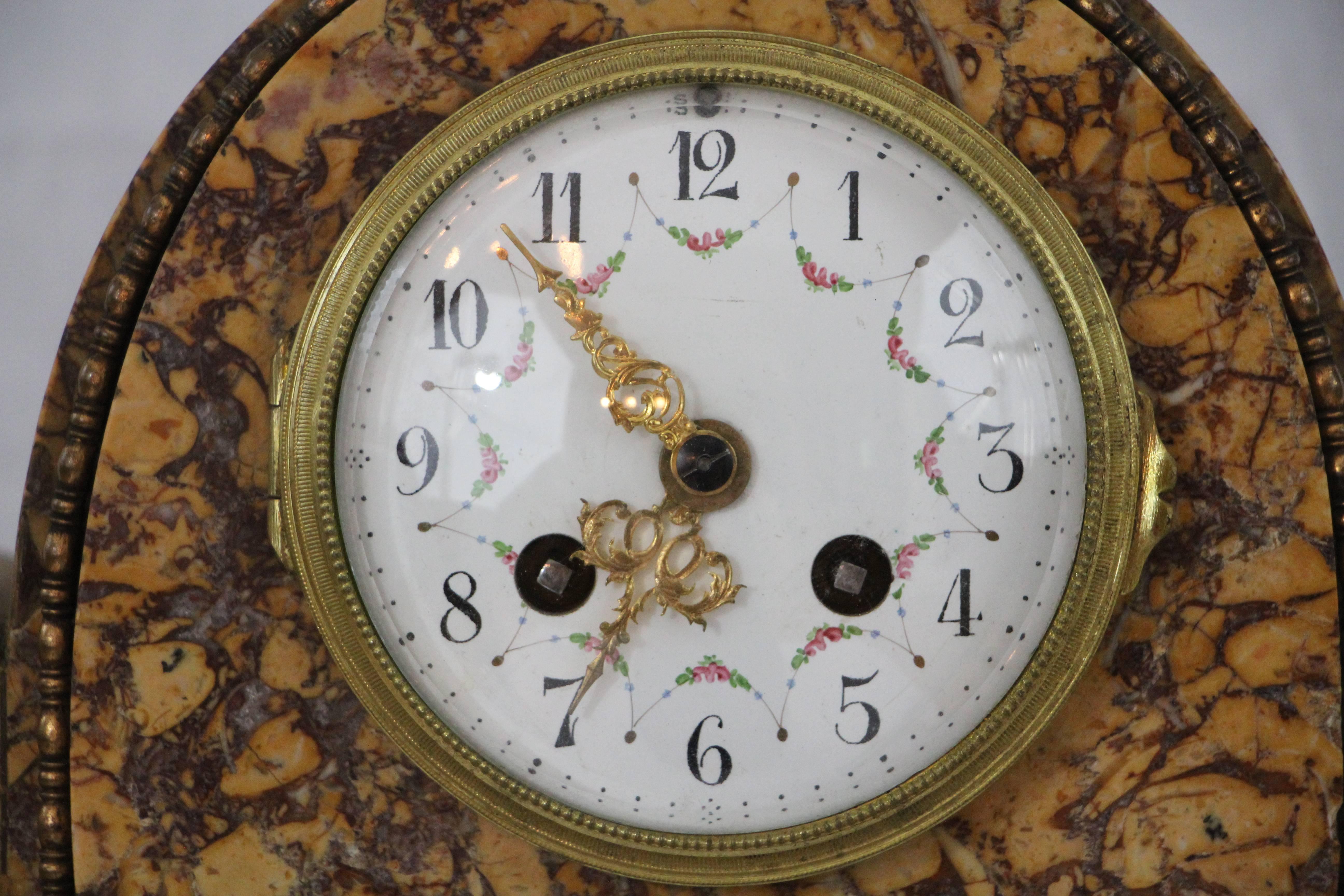 Art Deco mantel clock set. Orange-brownish marble with black accents. Strikes every hour and half hour. Enamel dial-plate with flower decoration. 
Vases: 8.5 inches high, 5.4 inches diameter.
Clock: 17 inches wide, 12.7 inches high, 4.2 inches