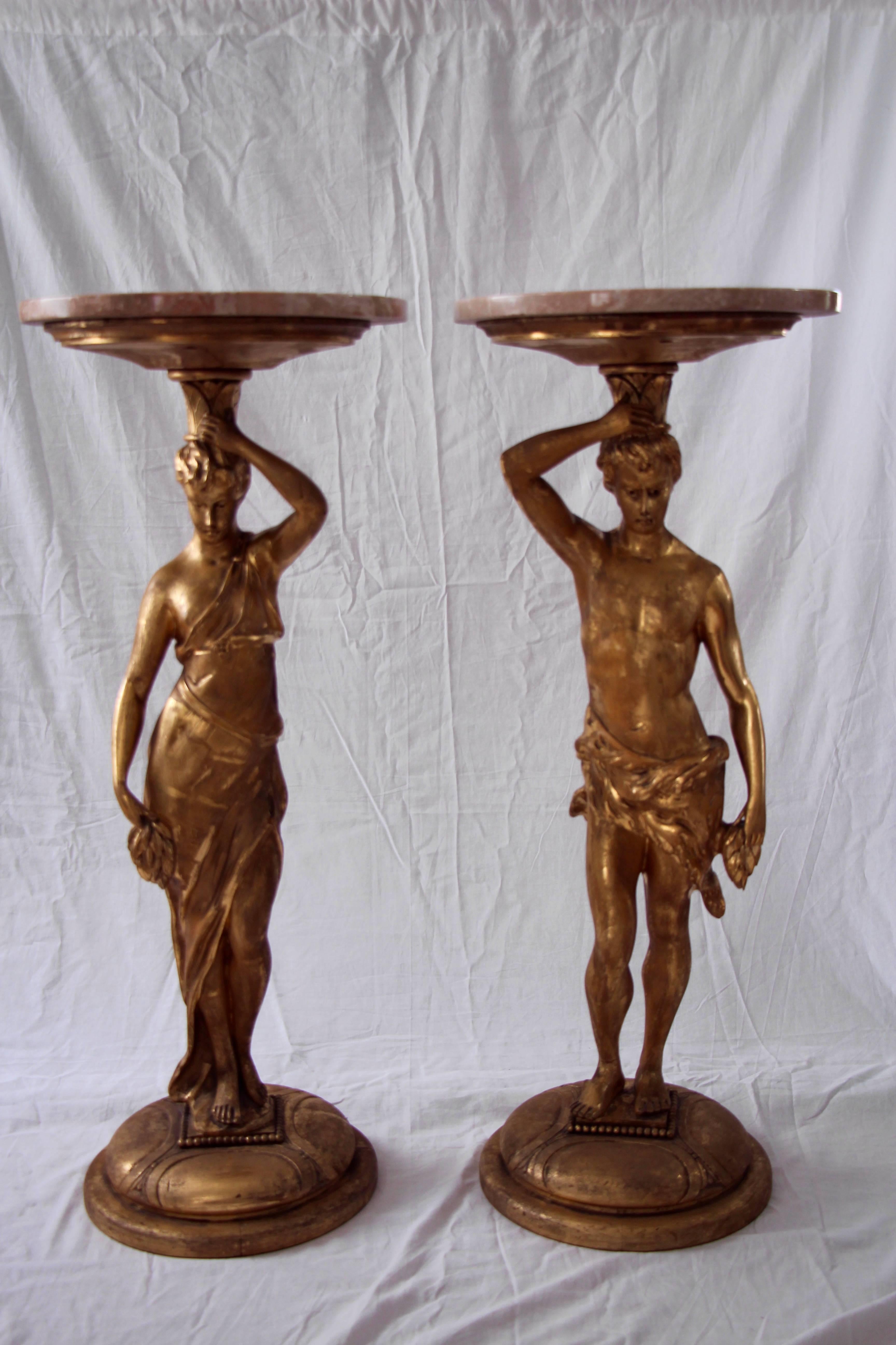Unique pair of side tables in form of a male and a female caryatid figure, with marble-tops. Beautifully carved and gilded wood.