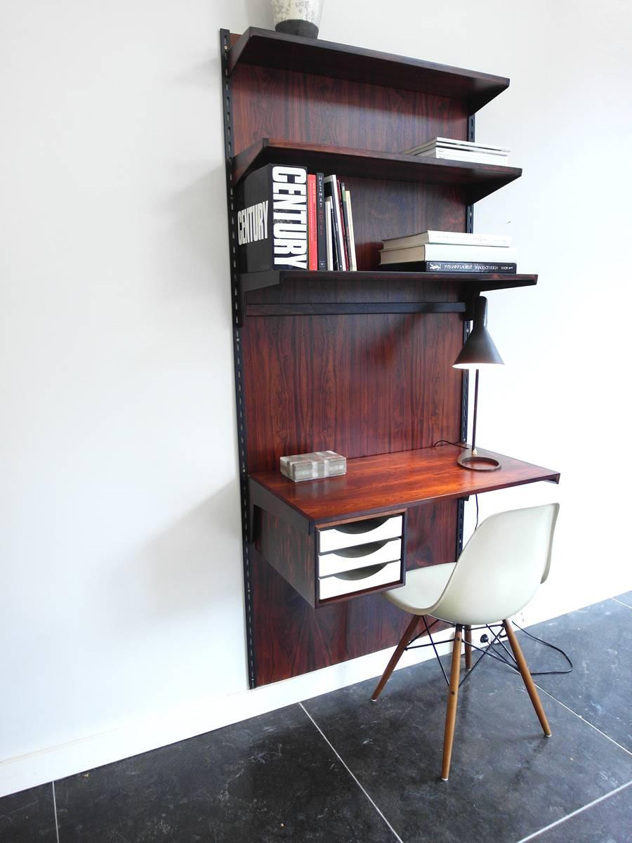 Danish modern shelving system with desk, designed by Kai Kristiansen for FM Møbler, Denmark, 1960. Very nice wall-mounted small desk with three white drawers. Beautiful rosewood grain patterns and three hand-carved adjustable shelves. All pieces