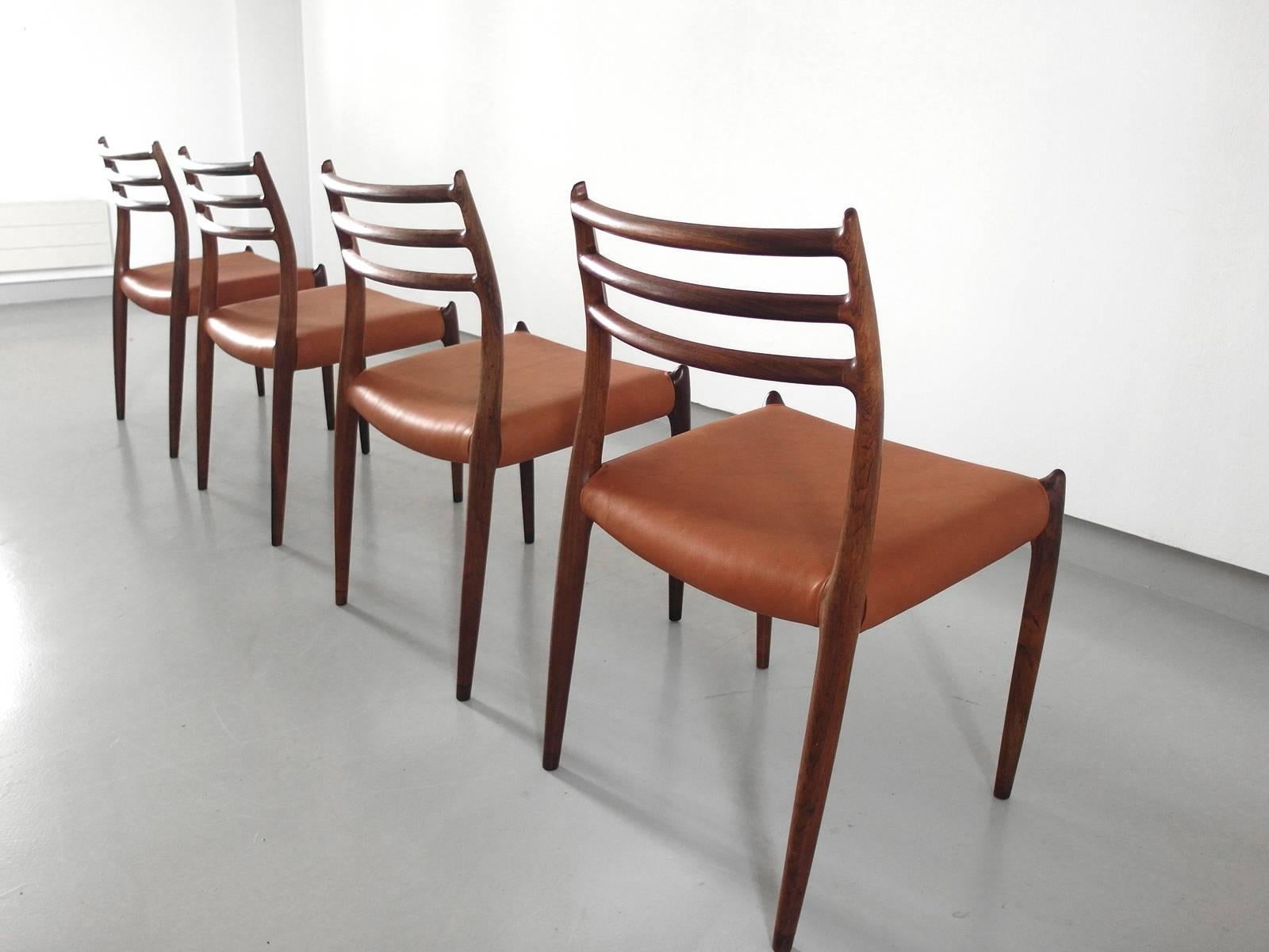Set of four elegant sculptural dining chairs Model 78 designed by Niels Otto Møller for J.L Møller, Denmark, circa 1965. The premium quality organic frames are made of rosewood. The seats are reupholstered in cognac brown leather. The Model 78