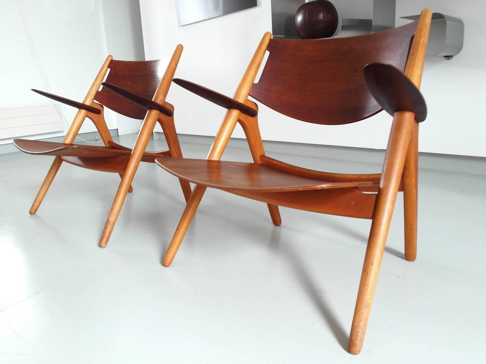 Amazing and rare pair of early lounge chairs model CH-28, or Sawbuck chairs designed by Hans J. Wegner for Carl Hansen, Denmark 1951. 
Beautiful old chairs in solid oak and teak plywood with wonderful wood grain and patina. Smooth clean lines and