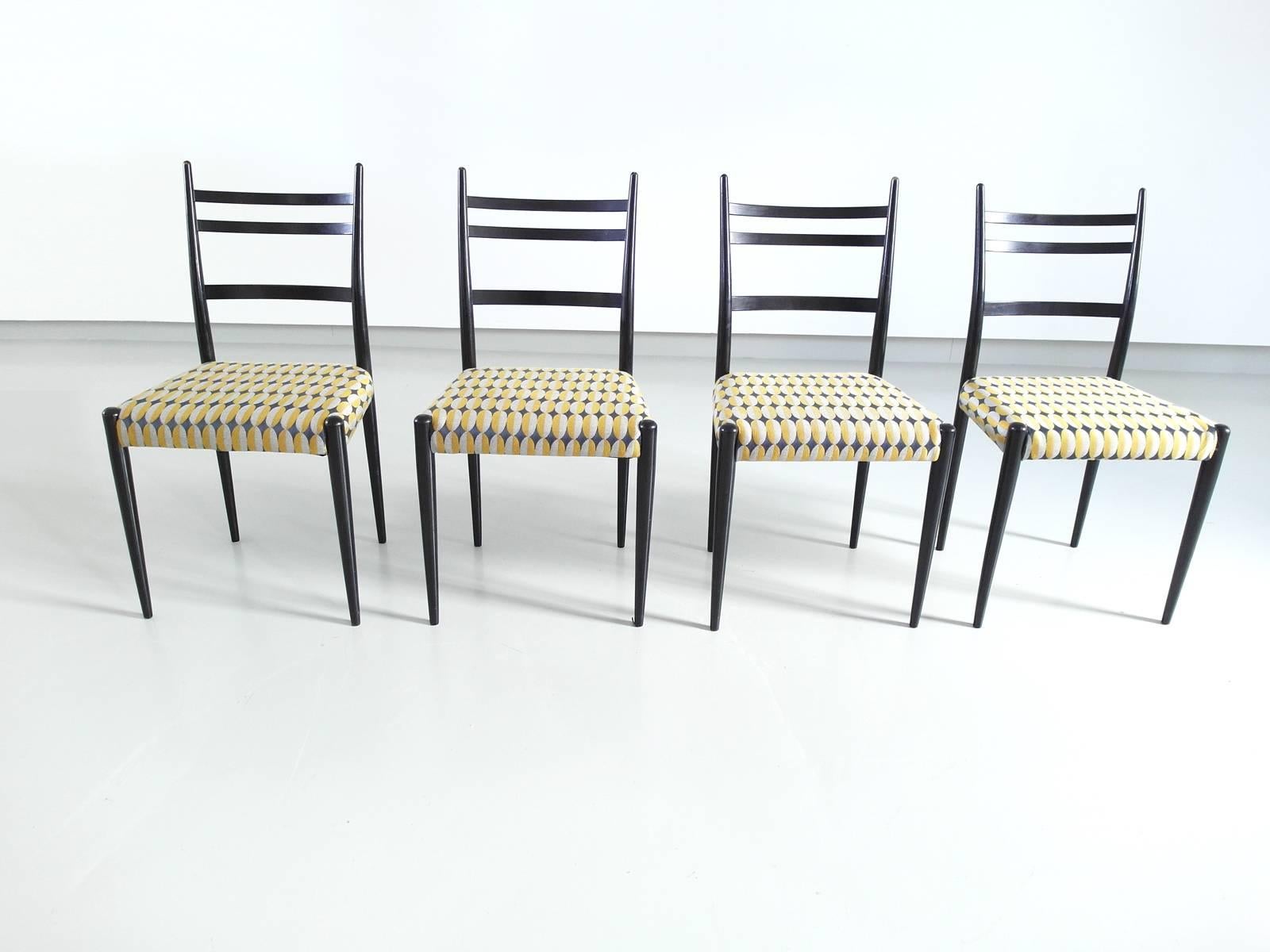 Very nice set of four Mid-Century Modern Italian dining chairs in the manner of Gio Ponti's Legerra chair. The chairs feature a sleek and elegant black wooden frame and are reupholstered with a great high quality graphic fabric in yellow and grey.