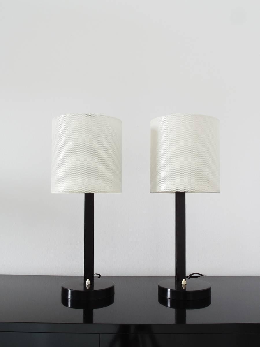 An absolutely stunning and rare pair of French Midcentury Modern table lamps in the style of Mathieu Matégot. Delicate white perforated metal shades and black colored bases. High quality, sturdy and heavy lamps with original switches. When lit, the