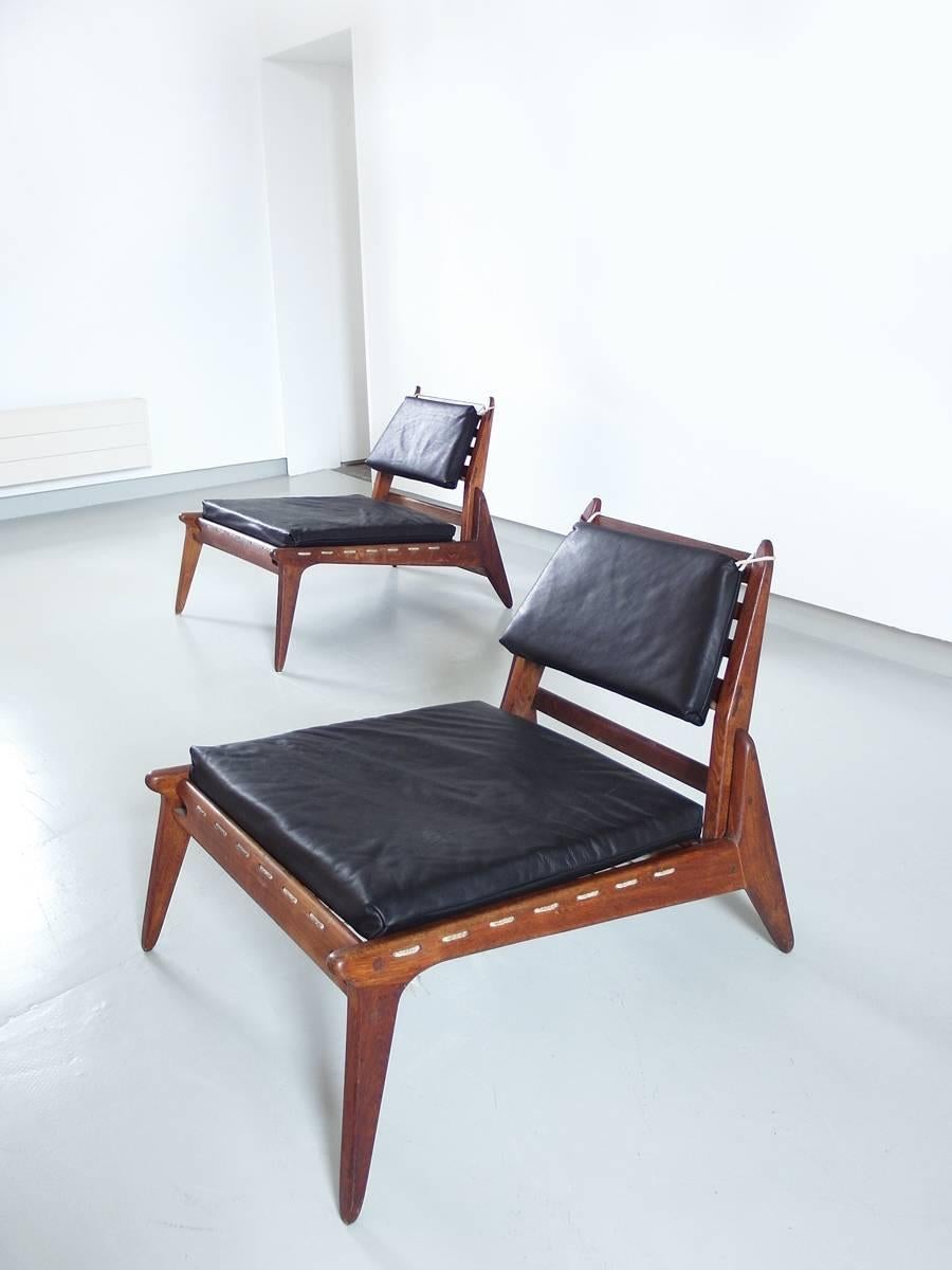 A pair of sculptural Hunting chairs in black leather and stained oak, Germany, 1950s. These hunting chairs show a very elegant and minimal design with great woodworking. A great open character is created by the beautiful trapezium shapes and tapered