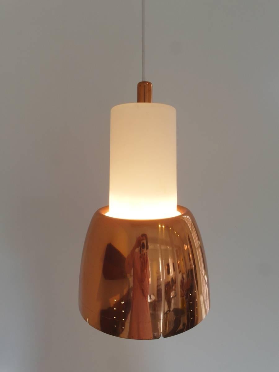 A red copper and Opaline glass pendant lamp model K2-16 designed by Paavo Tynell for Idman, Finland, 1950s. The lamp has an Opaline glass cylinder diffuser with a perforated copper lampshade.
Manufacturer's logo imprinted in the copper part on top.