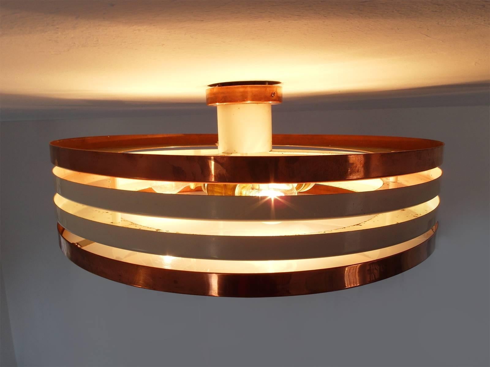 A Scandinavian Modern flush mount fixture by Itsu, Finland, 1950s. 
A three-light plexiglass and copper ceiling lamp consisting from four rings, creating an open structure in copper and white aluminium. The lamp spreads a very nice warm glow. A