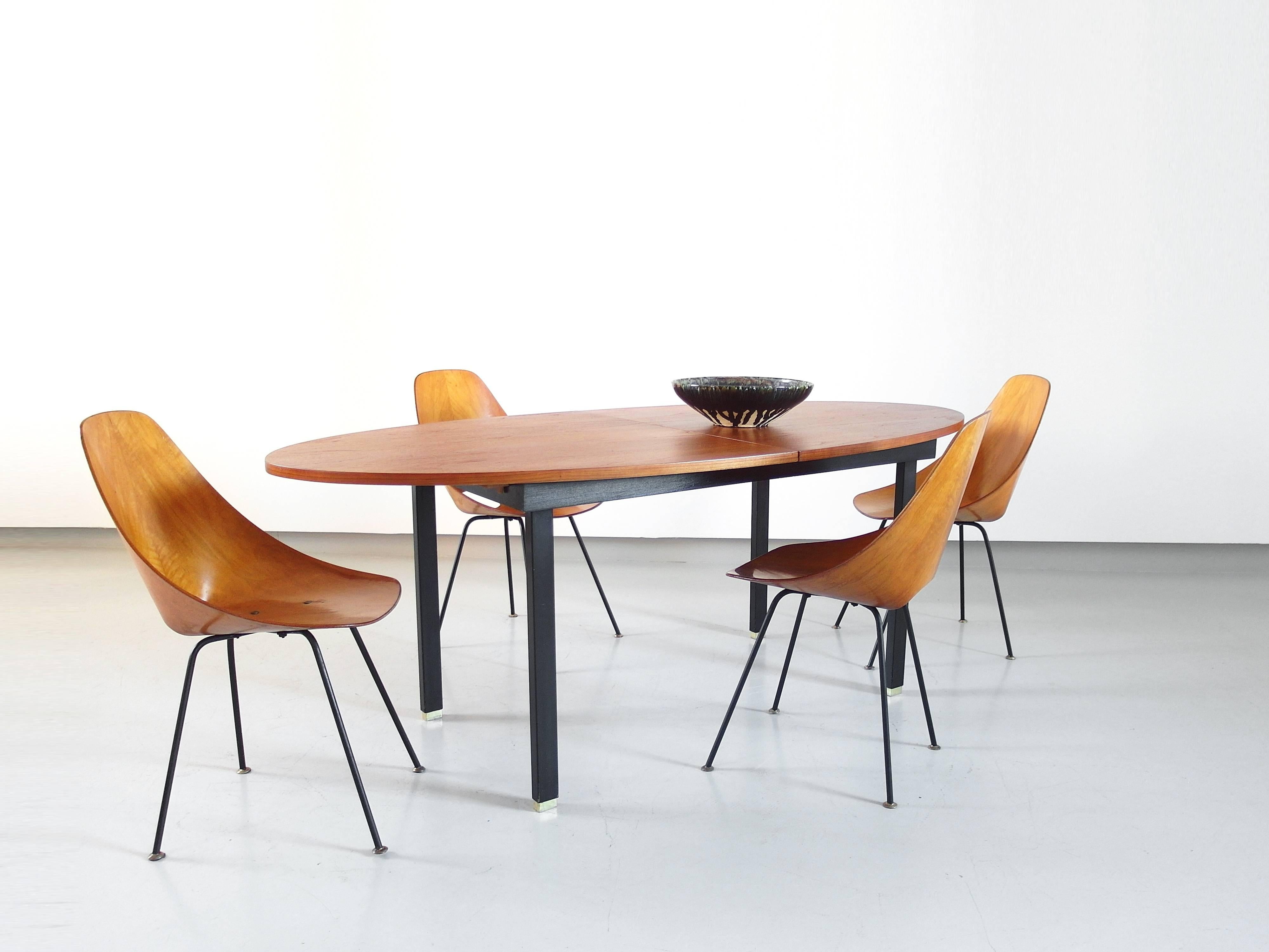 Refined oval dining table with a teak veneer extendable tabletop, Belgium, 1960s.
The tabletop sits on a black wooden frame and has black metal square tubular legs. The table extends from 195 cm to 240 cm. The refined brass feet are extendable as