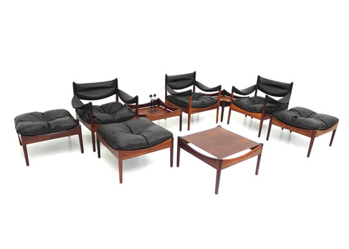 Sculptural Modus living room suite designed by Kristian Vedel and produced by Søren Willadsen, Denmark 1963. The suite consists of three solid rosewood low back easy chairs with original black leather upholstery with three matching ottomans with