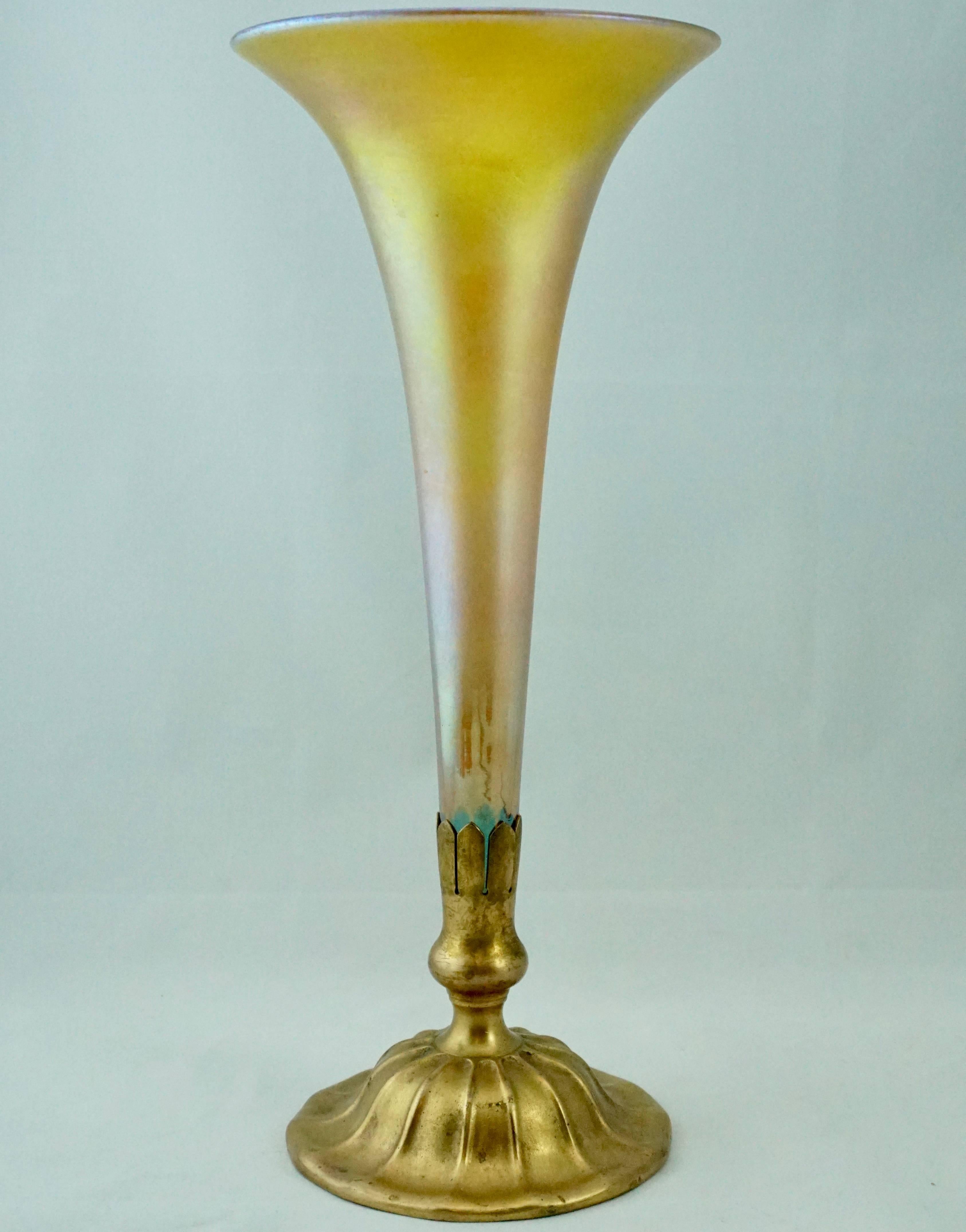 Beautiful gold favrile glass trumpet vase that sits snug in a gilt gold patinated bronze Louis C Tiffany Furnaces Inc. New York base. A beautiful Art Nouveau decorative piece.

Measures: Height 15 inches
Width 6.25 inches.

Condition: Very good with