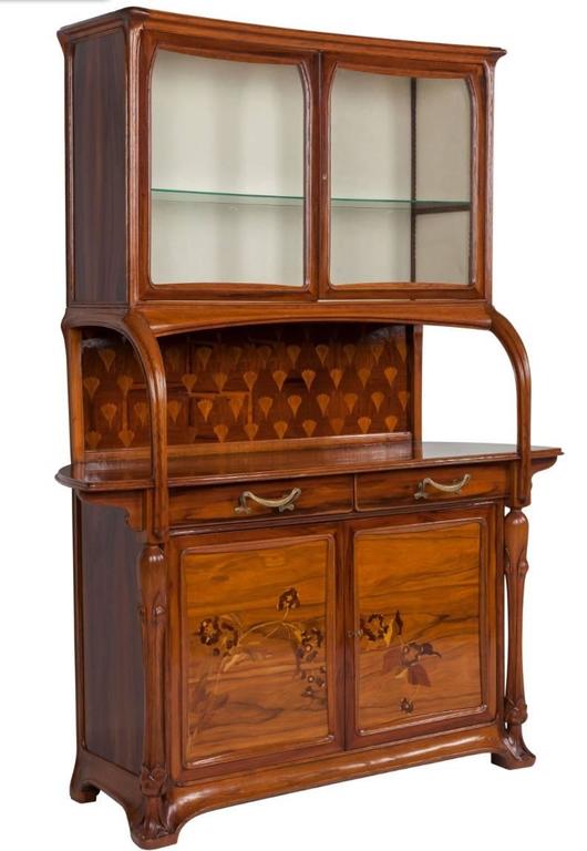 Elegant French vitrine cabinet signed by renowned Art Nouveau designer Louis Majorelle. The cabinet is composed of mahogany, walnut and multiple exotic woods and is decorated with floral inlay and various naturalistic botanic carvings characteristic