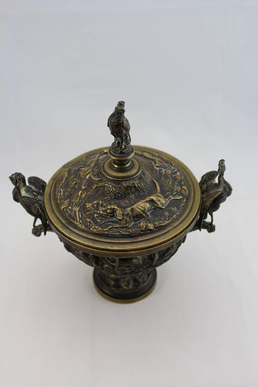 Bronze covered urns, coupe aux cigognes, avoid, the bodies cast with scenes of peasants and young to one side and rabbits and young on the other, the lids with a hunting scene of dogs chasing a fox, the lid finial formed as a perched bird of prey
