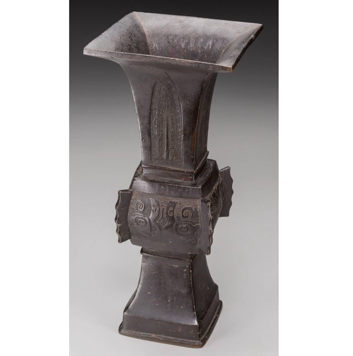 
A Chinese bronze gu-form vase. 17-18th century; 
14-1/2 inches high (36.8 cm.)

The beaker-form vase with incised key decoration within cartouches to the neck, bulbous mid-section with stylized dragonheads within key borders, protruding bamboo