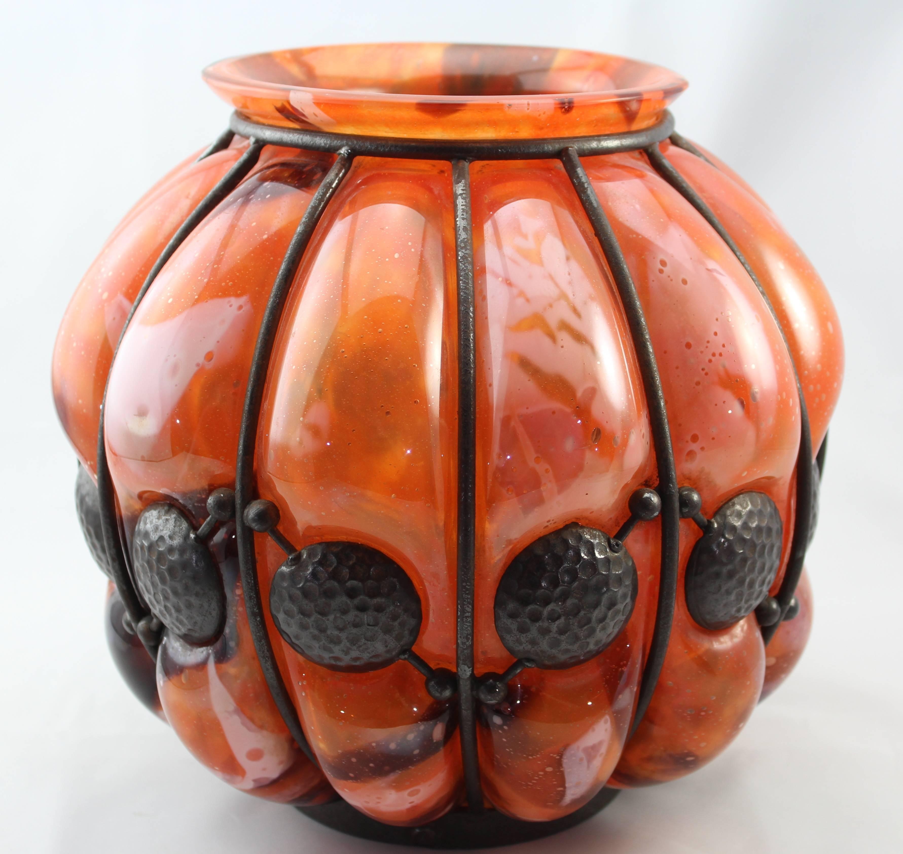 Daum Nancy and Louis Majorelle Art Deco hammered iron and glass blown-out vase.
First quarter 19th century, French.

Composed of mottled orange, white, orange, burgundies and amber glass blown into a cast iron hammered cage with dimpled golf