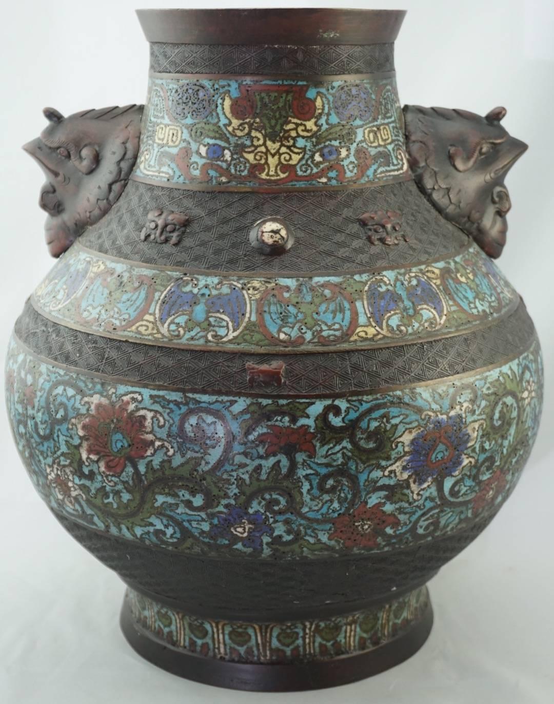 Qing Chinese cloisonne bronze decorated vase 19th century. Champleve cloisonne designs of bats, flowers and archaic features. Detailed design work in four bands around vase with masks. Two applied avion bird or rooster heads.

Height: 14.24