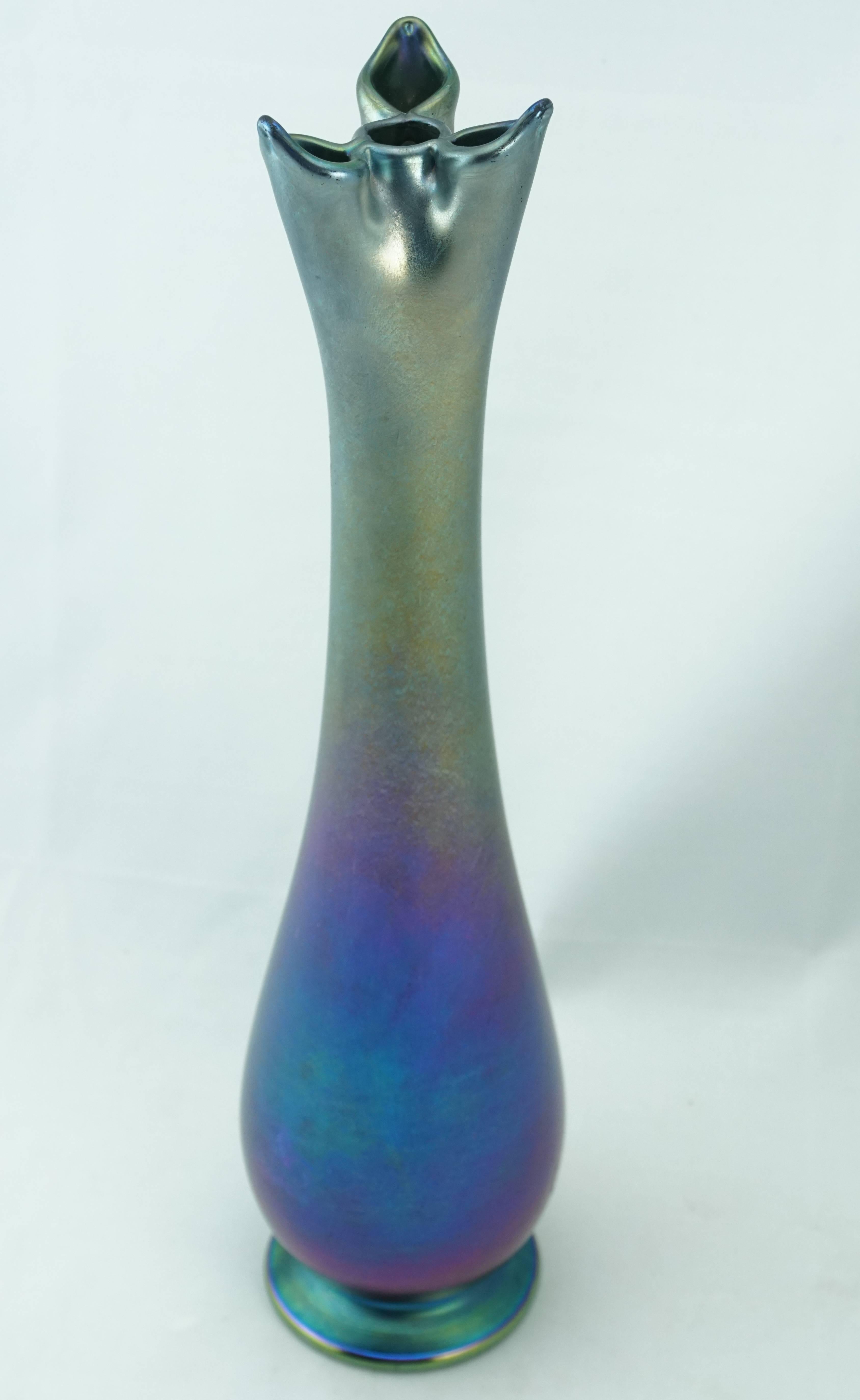 Louis Comfort Tiffany (American, 1848-1933), Turn of the century. A Tiffany Studios iridescent blue favrile art glass vase of elongated baluster form with folded glass at mouth forming four stem Chambers, the three outer Chambers with pointed edges,