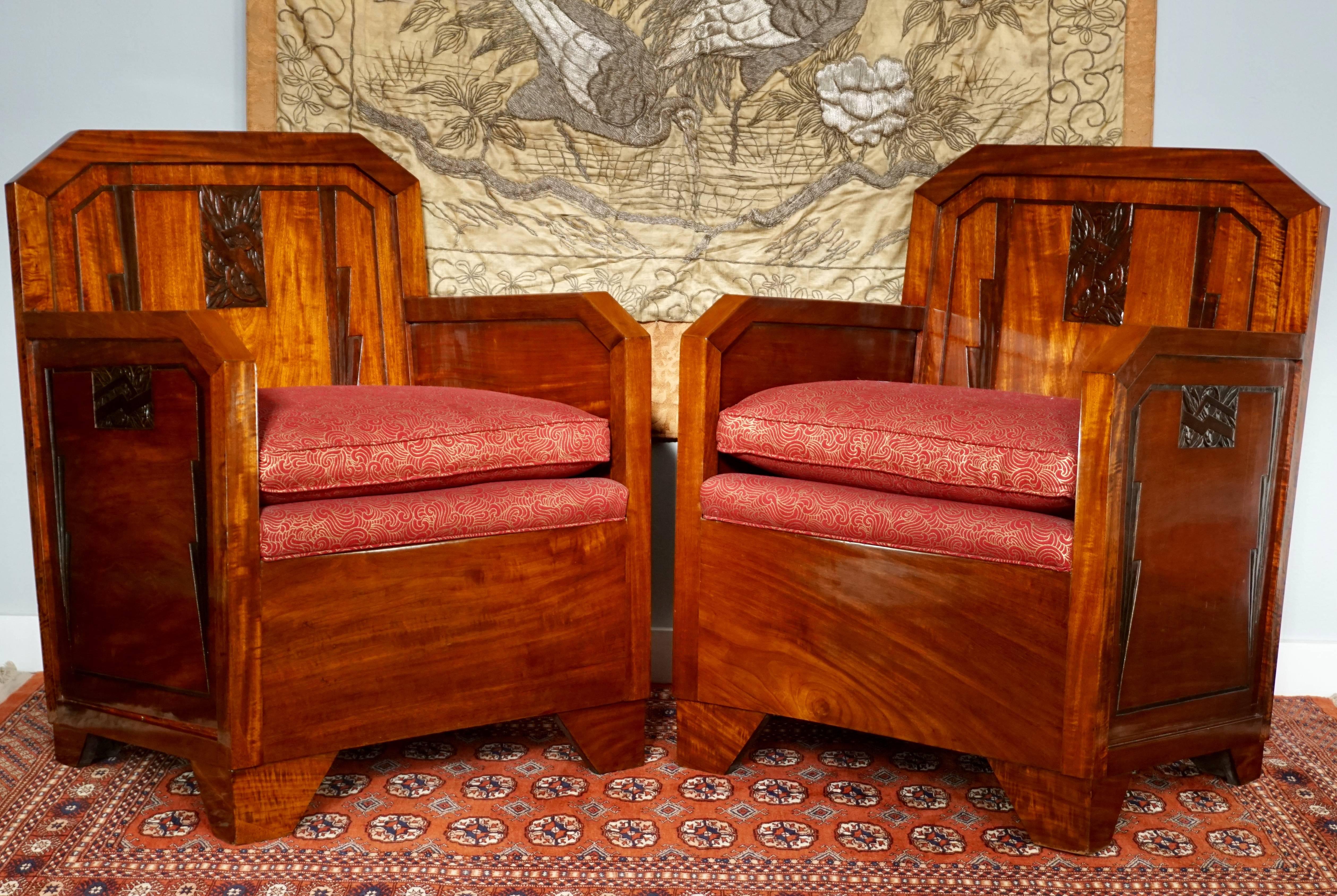 A pair of French Art Deco Bergères. Made of heavy, solid mahogany wood construction with hand-carved Art Deco decorated accents and lines. Upholstered in red fabric. Perfect for the cinema, movie or TV room or man cave. The quintessential Lounge