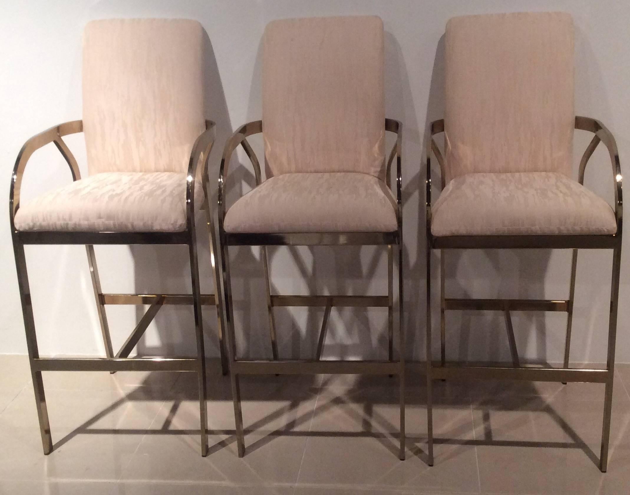 Amazing set of three (3) Hollywood Regency, vintage DIA, Design Institute of America, gold brass barstools with arms. These have their original upholstery which will need to be newly upholstered. There is one small area which is pictured that has