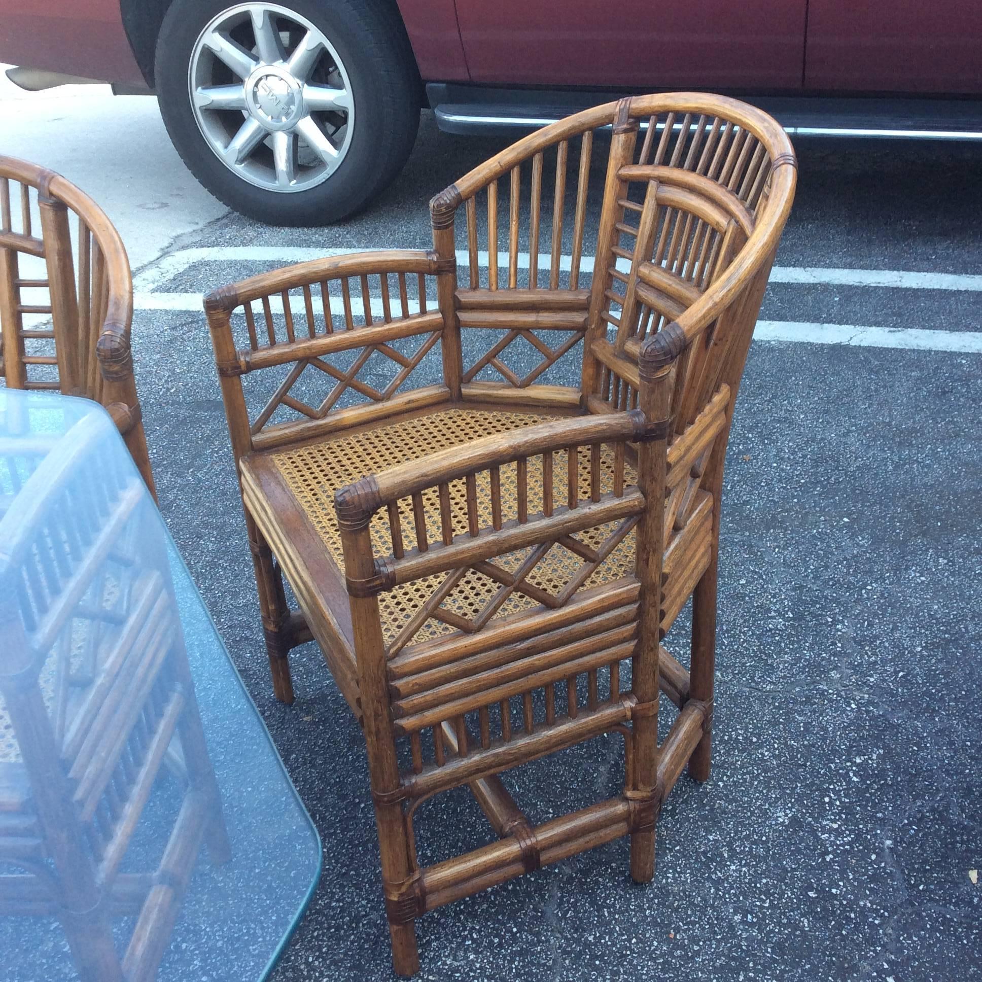 Vintage beautiful Brighton Pavillion style rattan dining or game table set. This set includes four rattan, faux bamboo armchairs, rattan table. This is in excellent condition. Great Chinese Chippendale pattern with a chinoiserie feel. Glass not