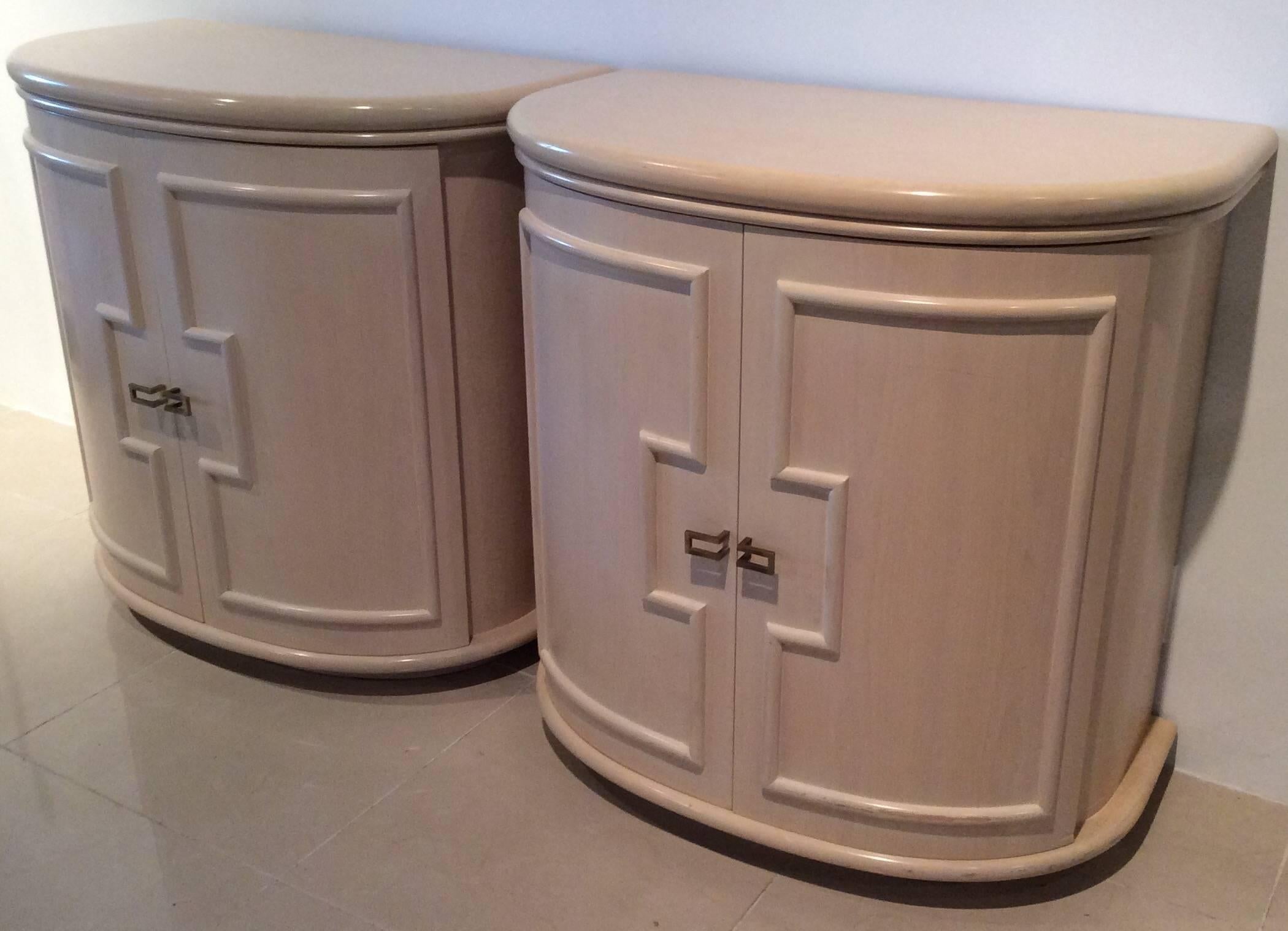 A vintage pair of Hollywood Regency demi lune, French curved door fronts, brass hardware, solid wood, Greek key style trim, oversized chests from Palm Beach. These are solid wood with a shelf inside. Original vintage finish which has a few scuffs to