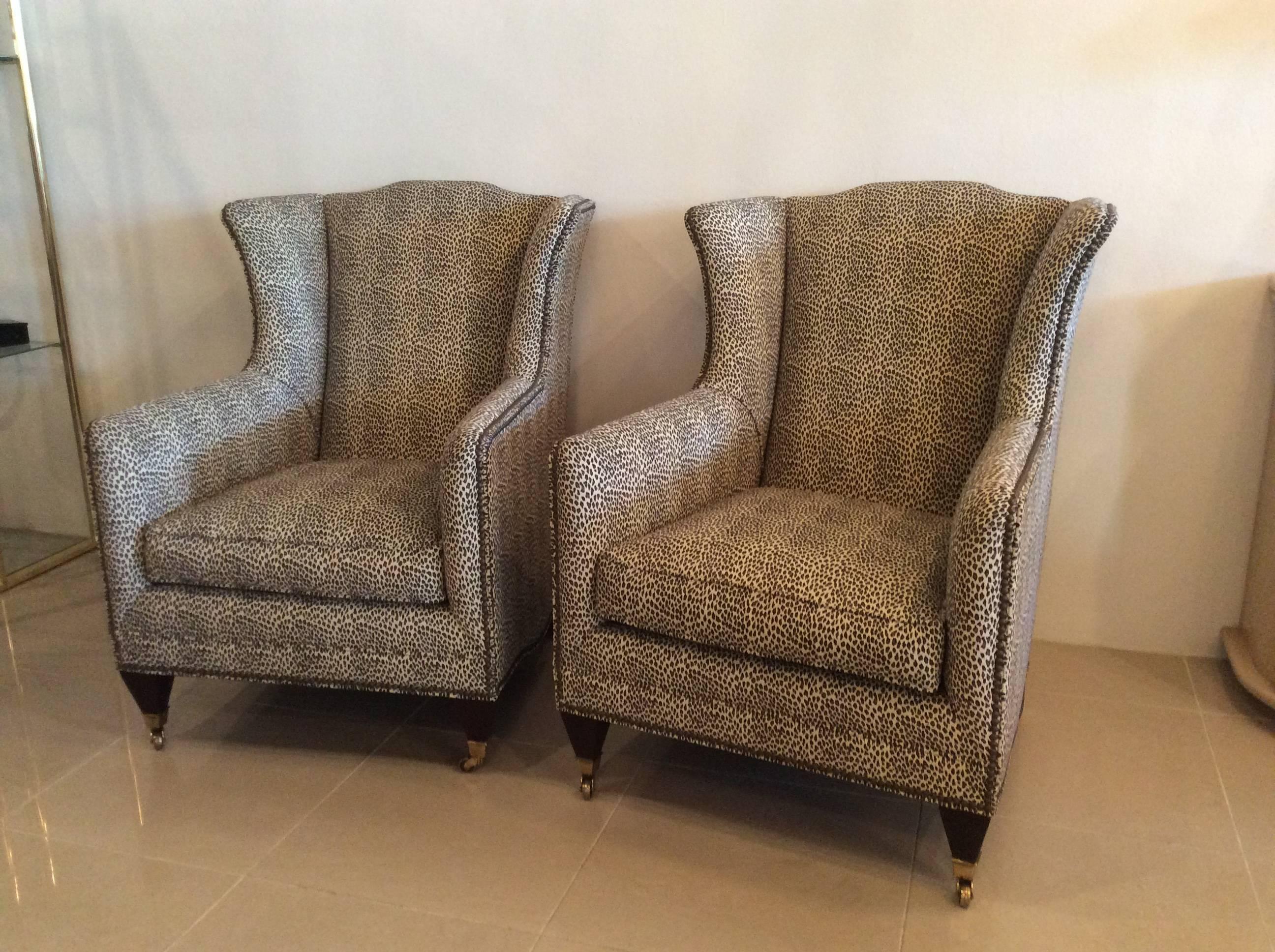 Amazing pair of vintage wingback arm chairs, club, lounge by Henredon Acquisitions (tagged). Done in a fabulous custom animal print fabric with brass nailheads, wood feet with brass caps and castors. These chairs are in new condition and super