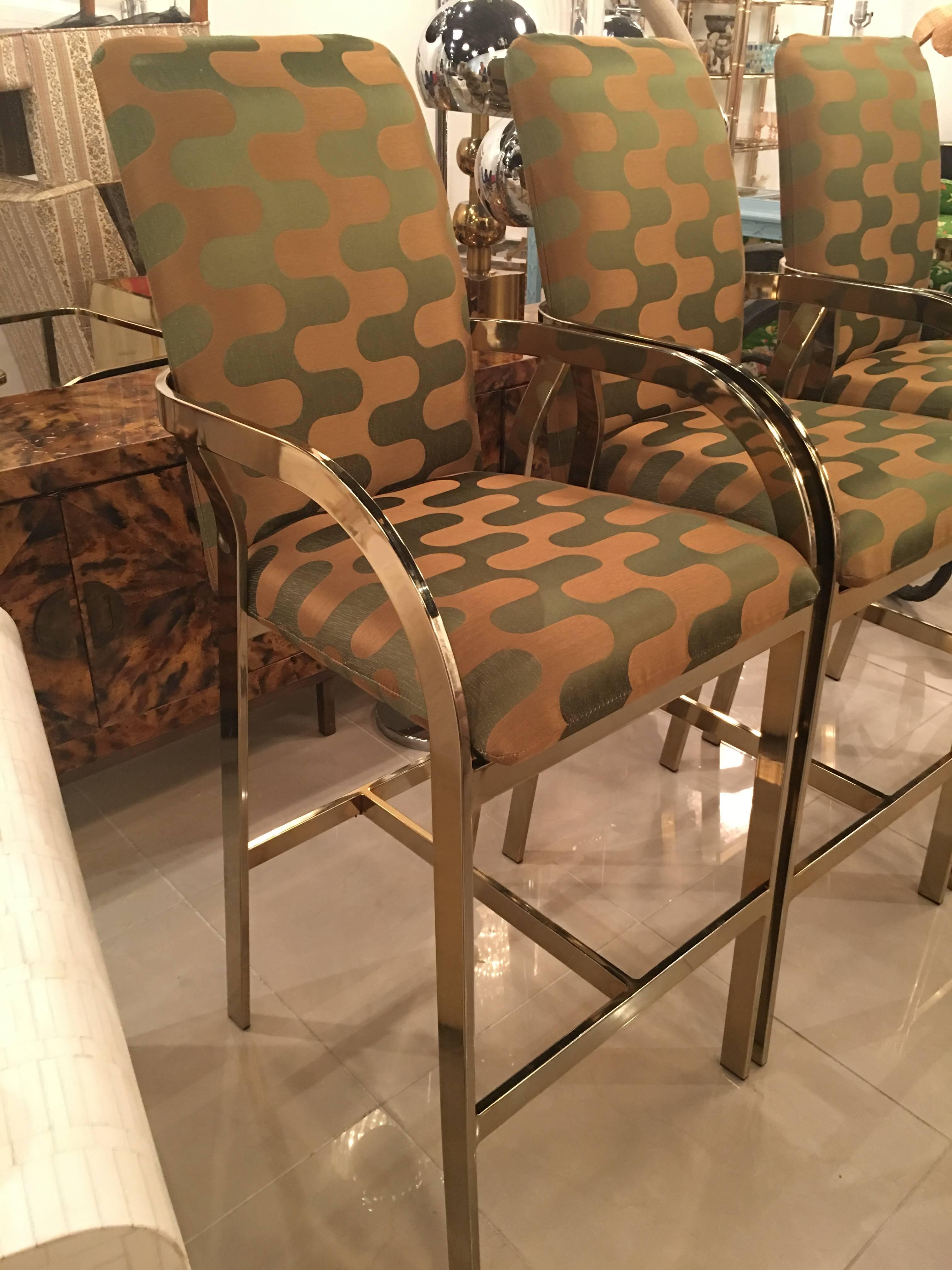 Amazing set of three (3) Hollywood Regency, vintage DIA, Design Institute of America, gold brass barstools bar stools with arms. These have been newly professionally upholstered in a Clarence House fabric. There is one small area which is pictured