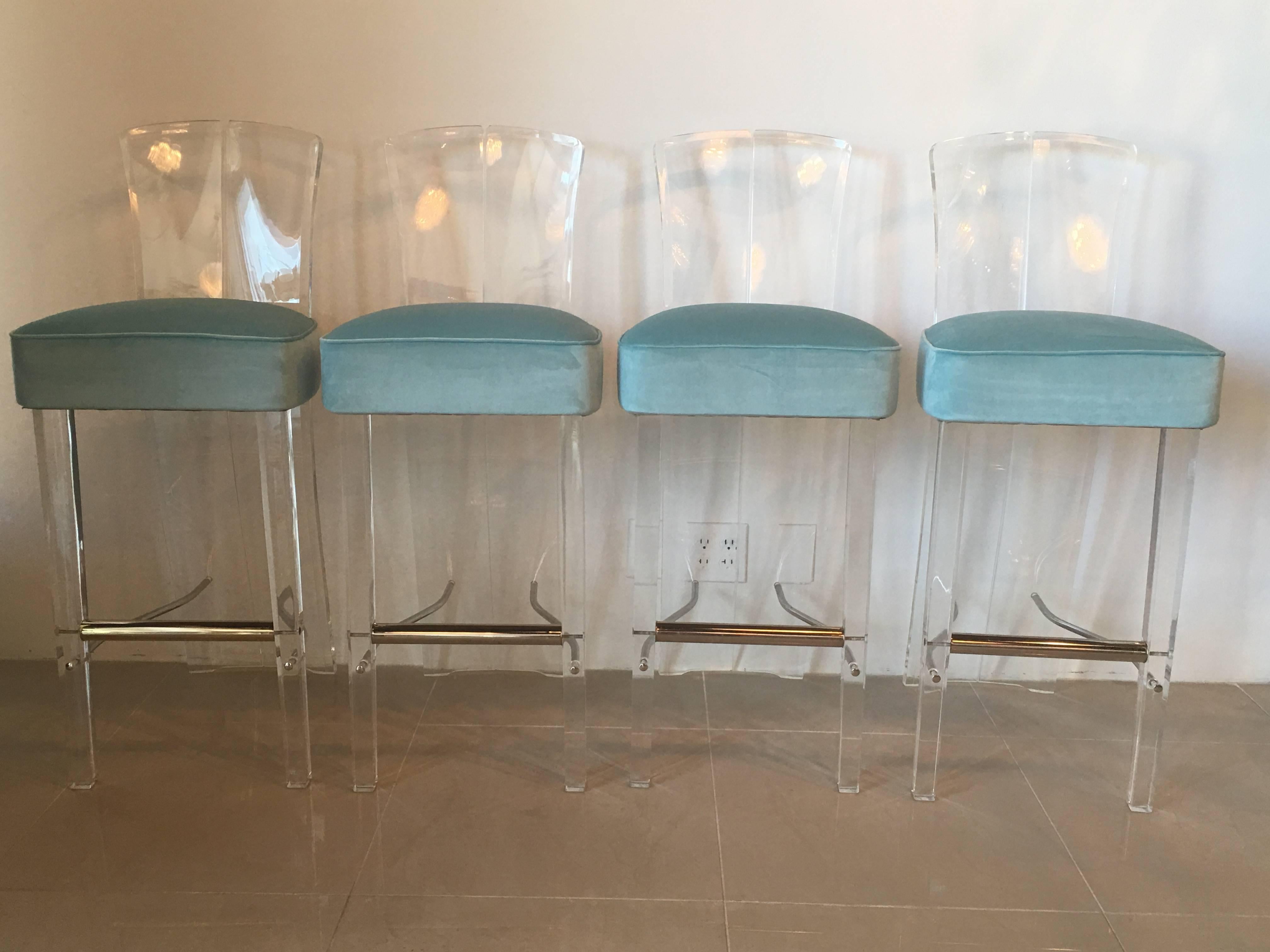 Set of four, Charles Hollis Jones style, amazing vintage Lucite and brass barstools, bar stools. The Lucite and brass have been polished and the blue velvet upholstery is new. There is some minor crazing around some of the screws and a few scratches