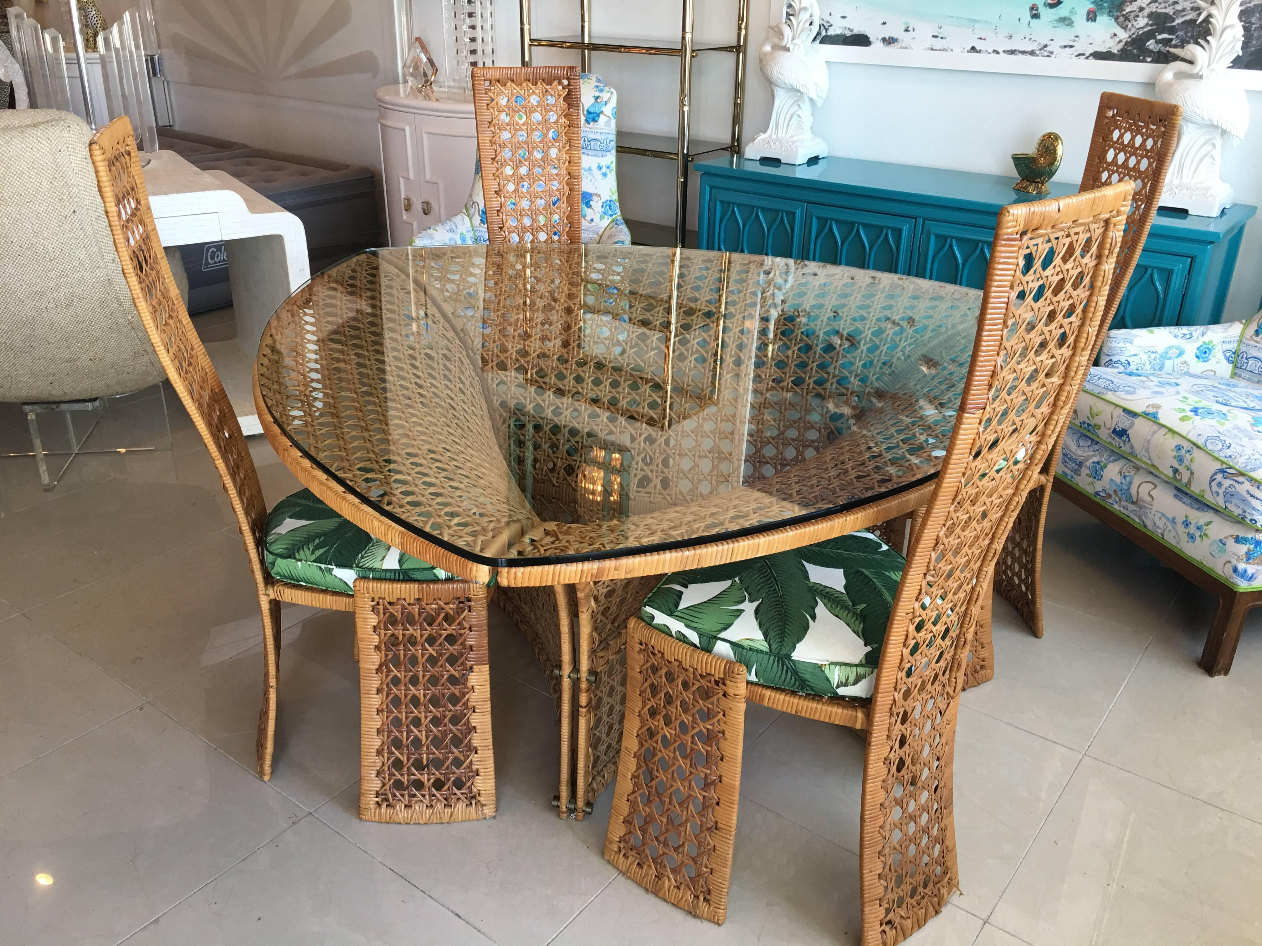 Vintage dining set by Danny Ho Fong. Set includes: rattan, wicker, triangular cane dining room table with glass top and four side dining chairs with removable custom, new chair cushions done in an indoor/outdoor upholstery.  No damage or breaks to