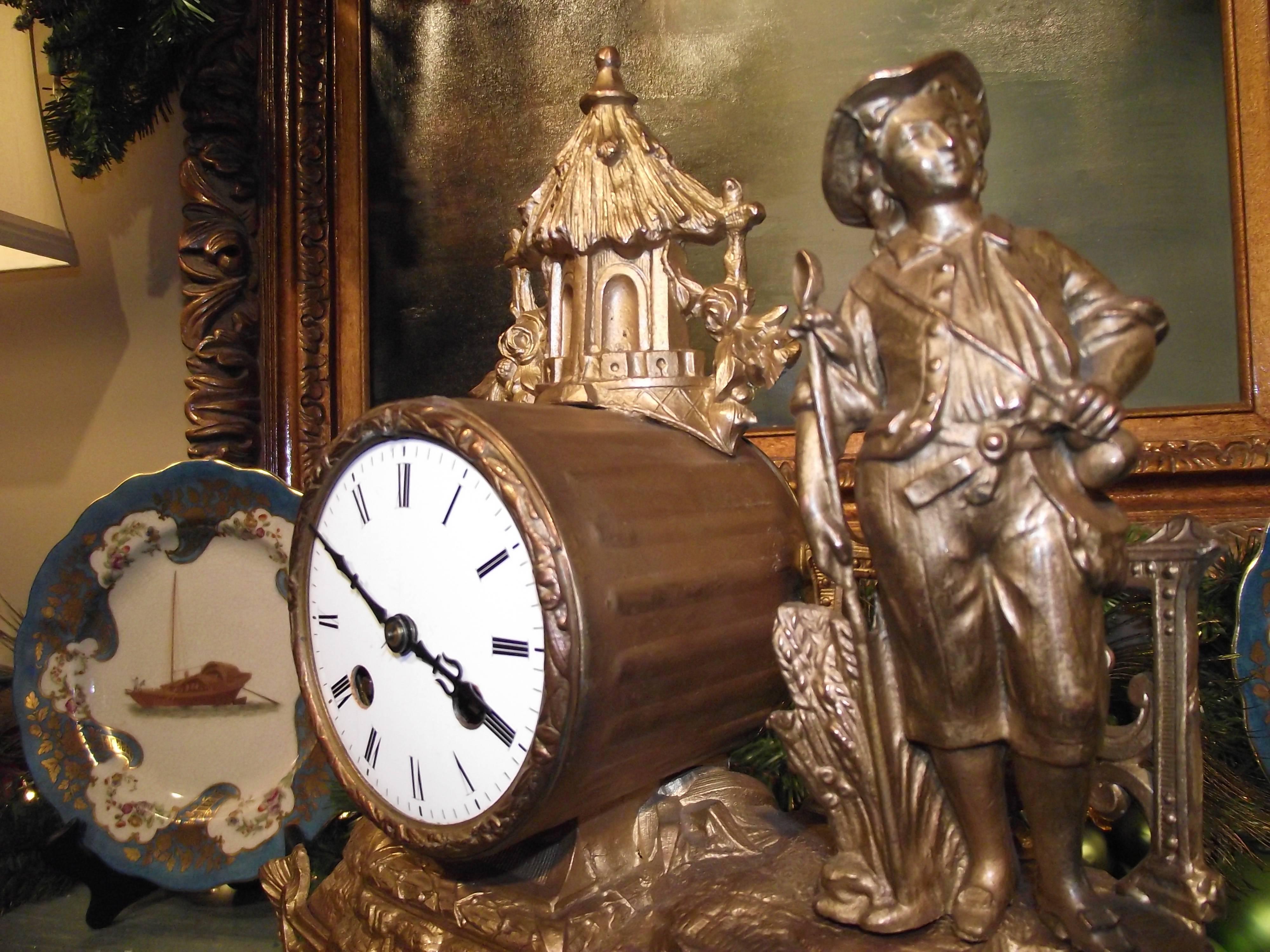 This beautiful spelter antique French clock honors the Agrarian life style. A young farmer stands next to a growth of wheat with a seeding implement in one hand and a seed bag over his shoulder. Behind him is his thatched roof barn.

This clock