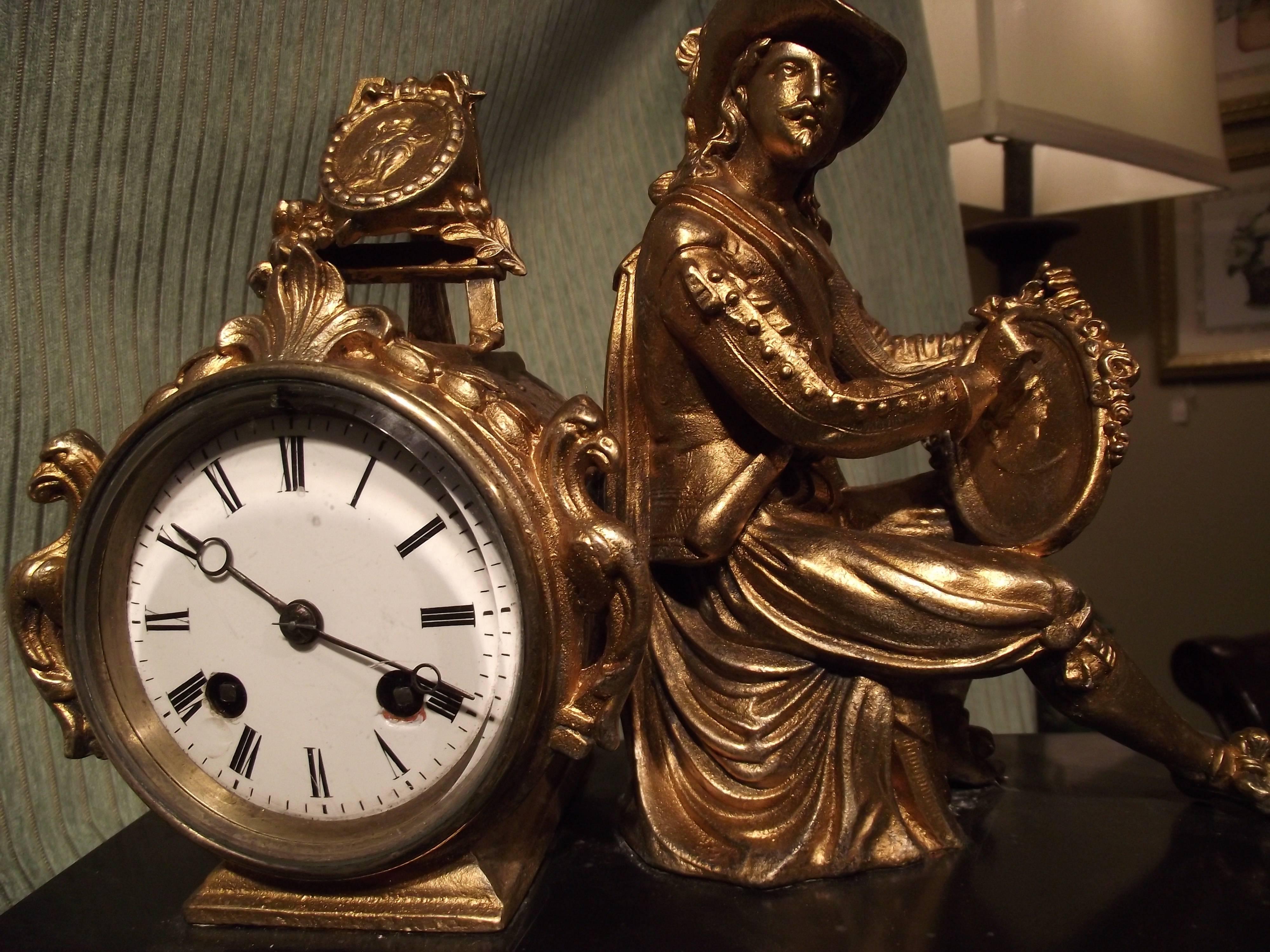 This beautiful French clock honors portrait painters. This dashing looking painter sits working on a painting while another sits on an easel behind him.

 A glass door covers the face of the clock which is in great shape. The back of the clock is